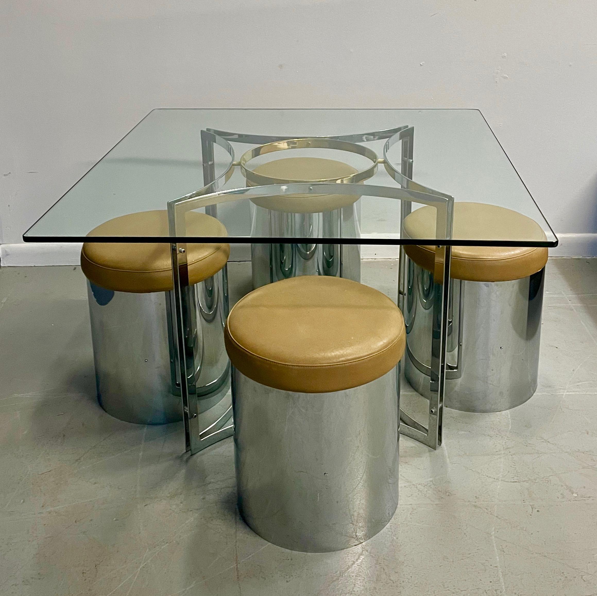 This brass and chrome set is the 1970s personified. A square piece of glass covers a chrome and brass base with four tan leather topped stainless steel round stools.