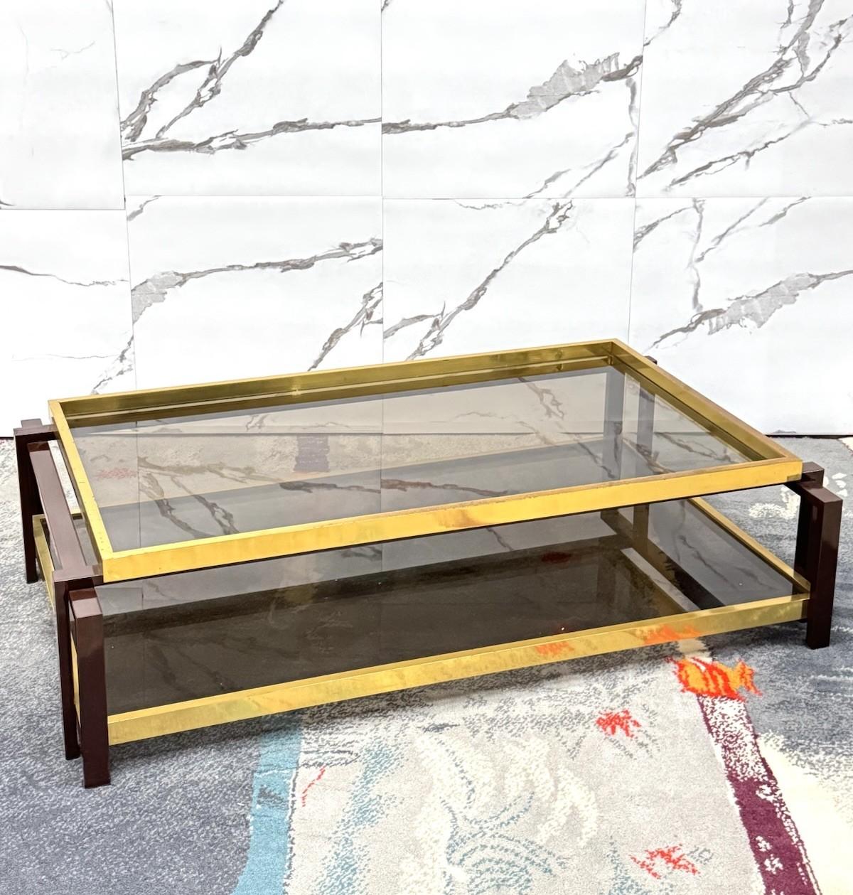 Iconico tavolo da salotto risalente agli anni ’70 in stile Hollywood Regency, caratterizzato da una sofisticata struttura geometrica in metallo laccato marrone e dorato. Il design pulito ed elegante si distingue per l’armoniosa combinazione di