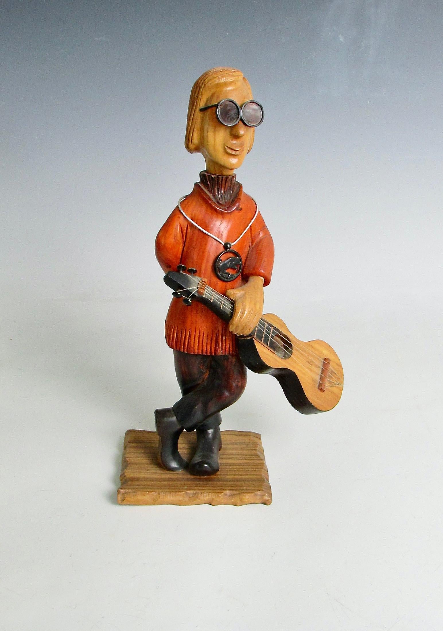 Caprichosa figura tallada de un guitarrista boho hippie folk rock  . Tallado a mano en Italia de finales de los 60 a los 70 . Esta es una de las muchas figuras talladas que representan oficios y aficiones .  Fabricado por la empresa Romer  Italia .