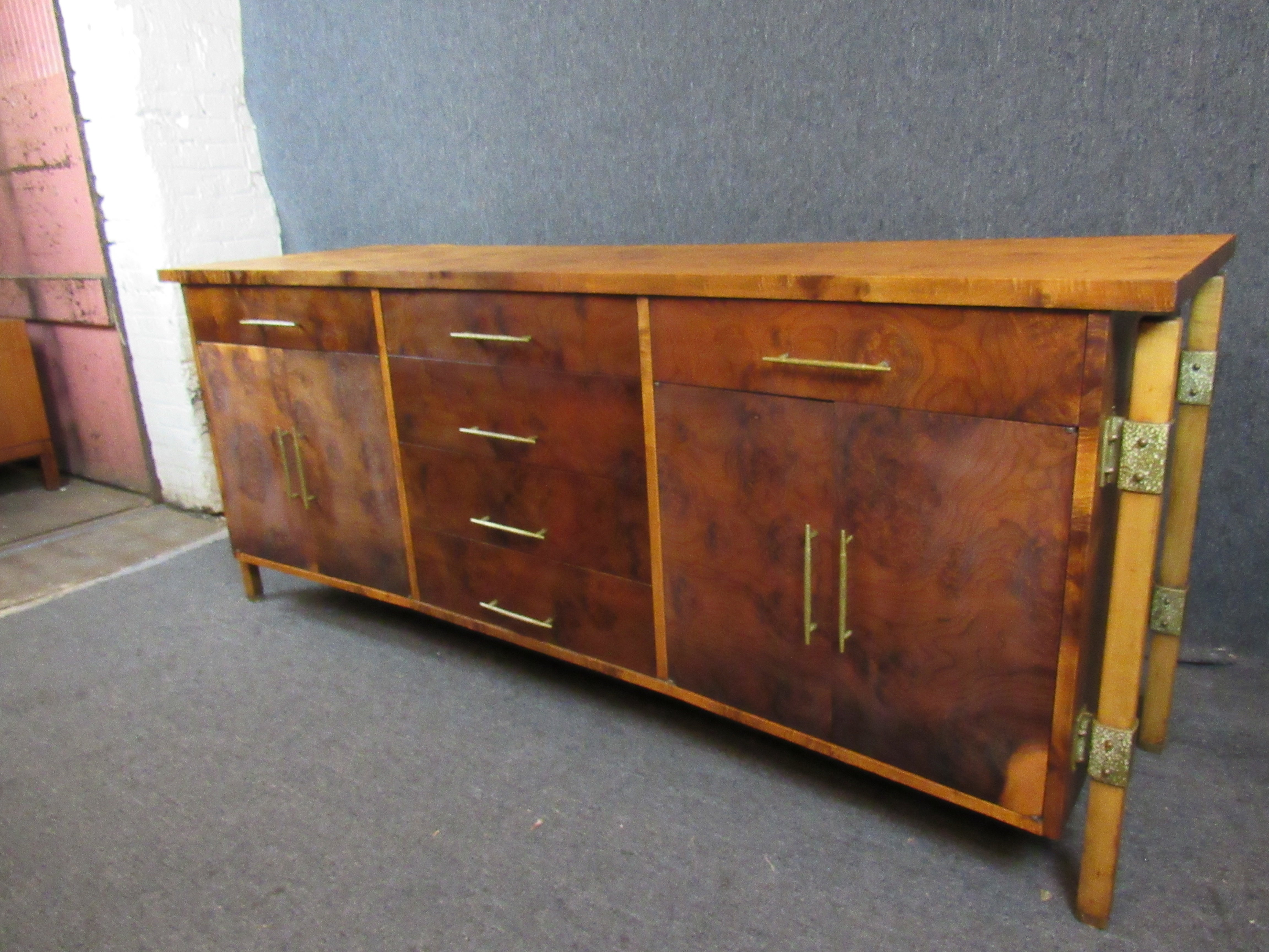 Gorgeous mid-century credenza from the highly regarded Romweber Furniture of Batesville, Indiana. Stunning two-tone burl wood with brass accents is sure to be a statement piece in any room of the home or office. Twelve large, pull-out drawers
