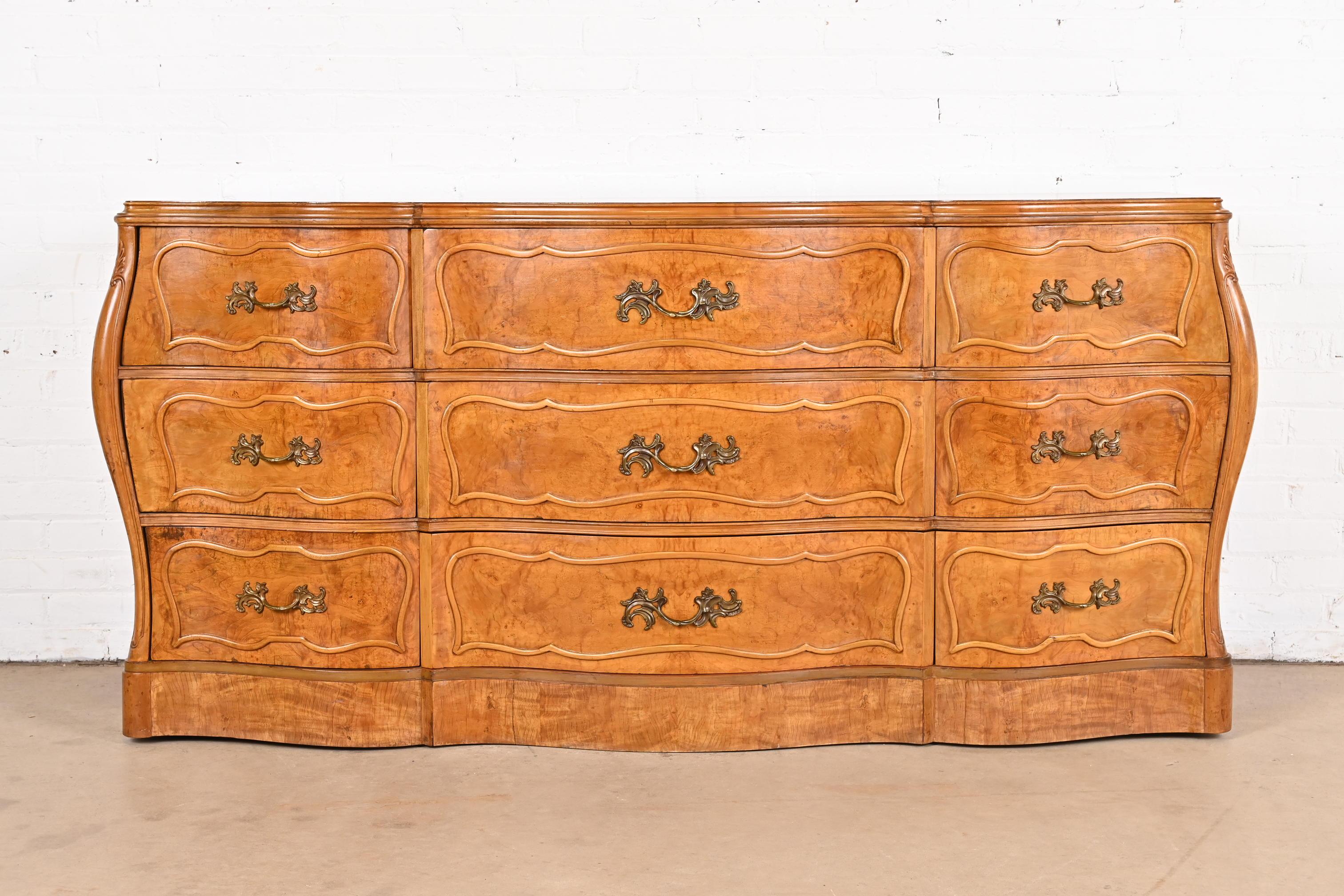 An exceptional French Provincial Louis XV style bombay form triple dresser or chest of drawers

By Romweber

Retailed by Hathaway's Furniture of New York

USA, Circa 1940s

Stunning book-matched burled olive wood, with original brass