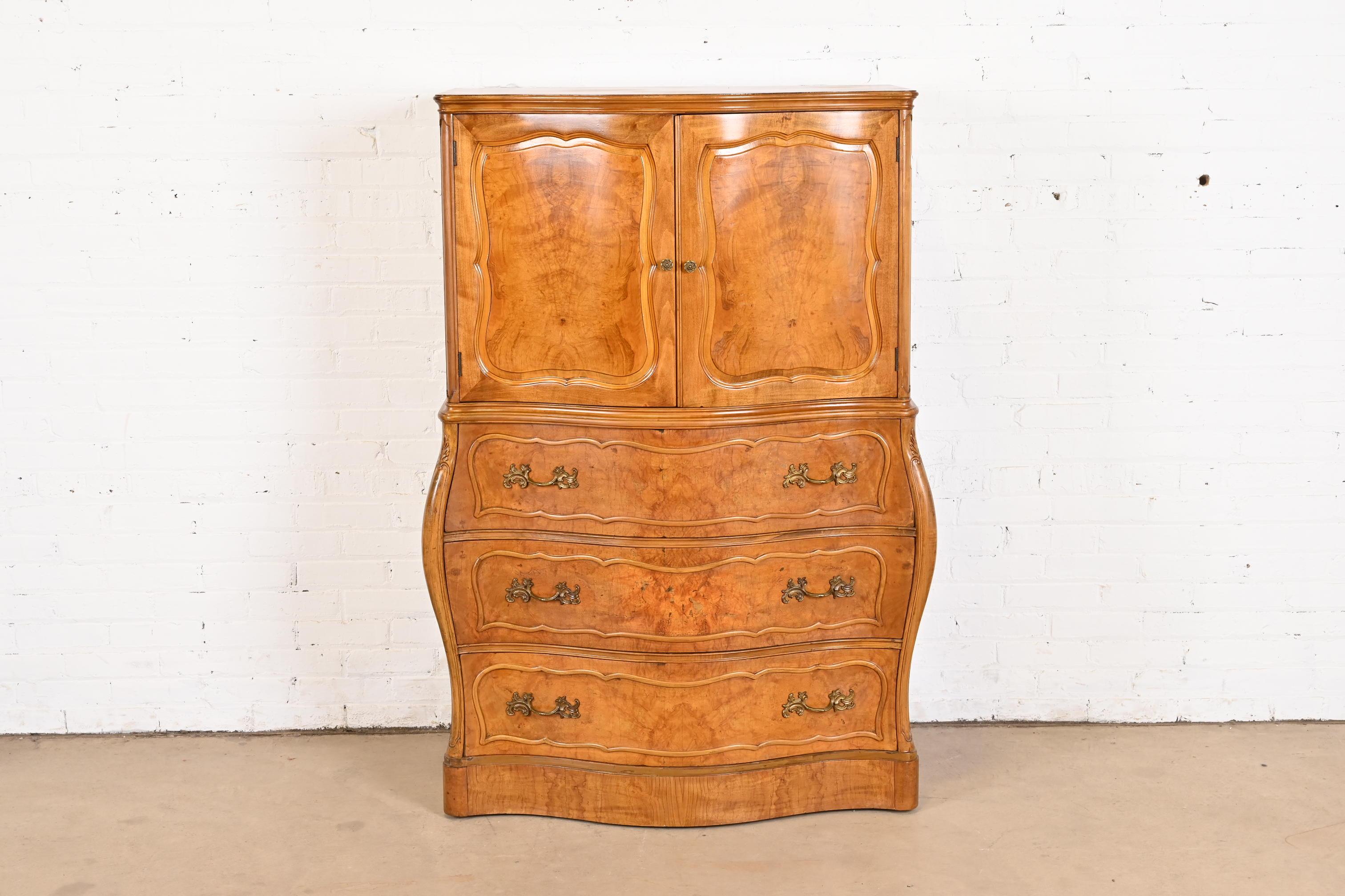 An exceptional French Provincial Louis XV style bombay form highboy dresser

By Romweber

Retailed by Hathaway's Furniture of New York

USA, Circa 1940s

Stunning book-matched burled olive wood, with original brass hardware.

Measures: 40