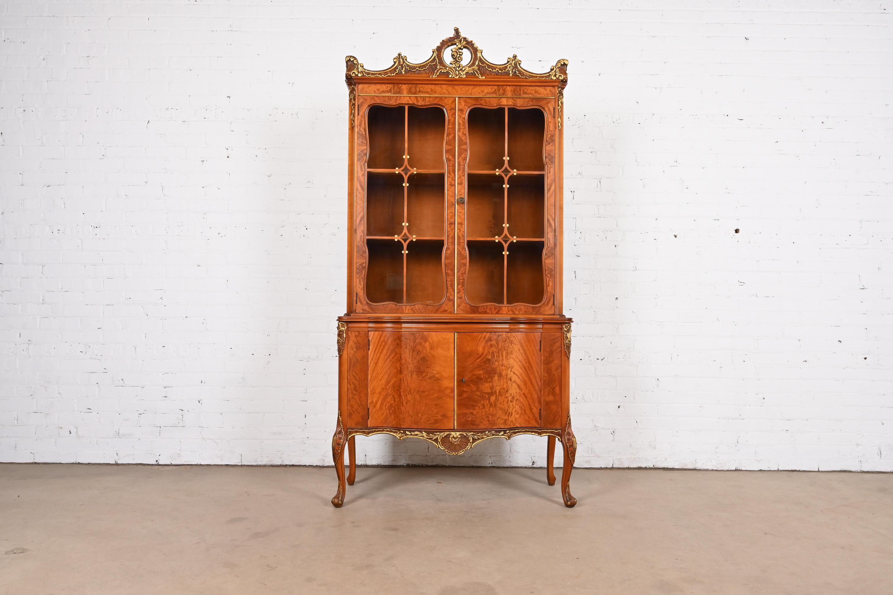 An exceptional French Provincial Louis XV style breakfront bookcase cabinet or dining cabinet

By Romweber

USA, Circa 1920s

Gorgeous book-matched exotic burled African avodire wood, with gold gilt details, mullioned glass front doors, and original