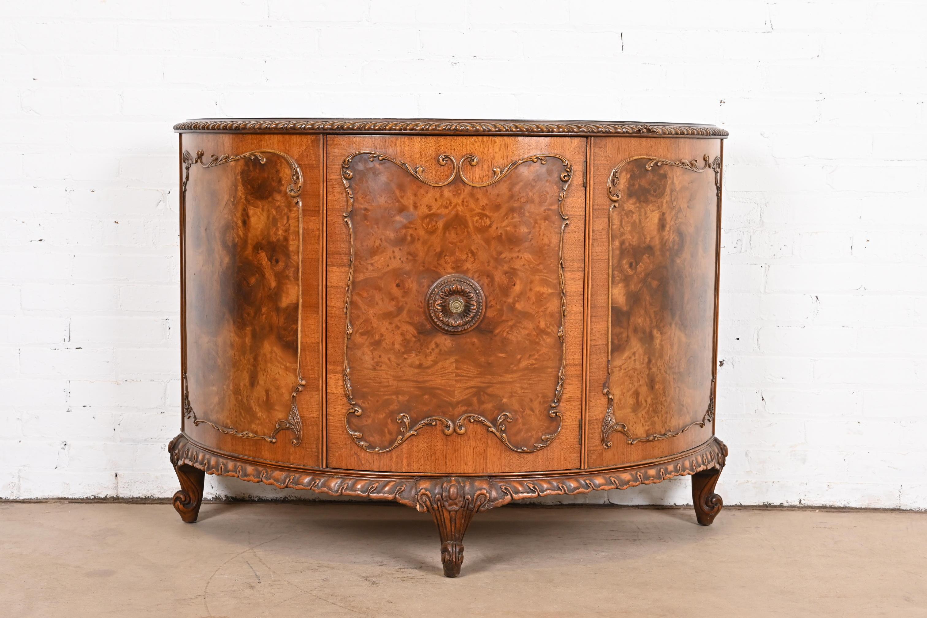 An exceptional French Provincial Louis XV style demilune bar cabinet or console

By Romweber

USA, Circa 1920s

Gorgeous exotic burled acacia wood, with ornate carved legs and trim, and original brass hardware.

Measures: 45.5