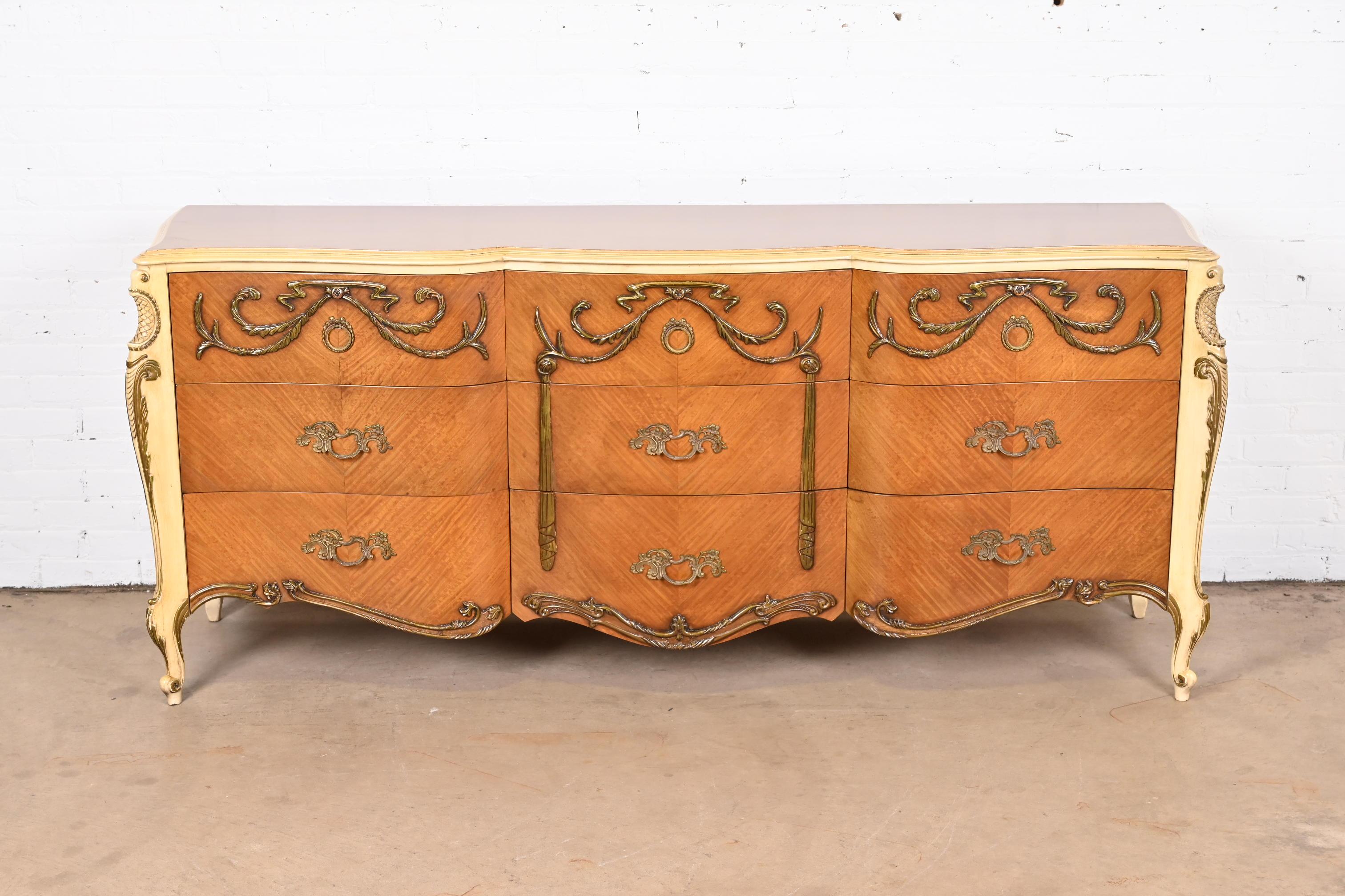 A gorgeous French Rococo Louis XV style triple dresser or credenza

By Romweber

USA, Circa 1940s

Book-matched satinwood, with painted trim and details and original brass hardware.

Measures: 77.75