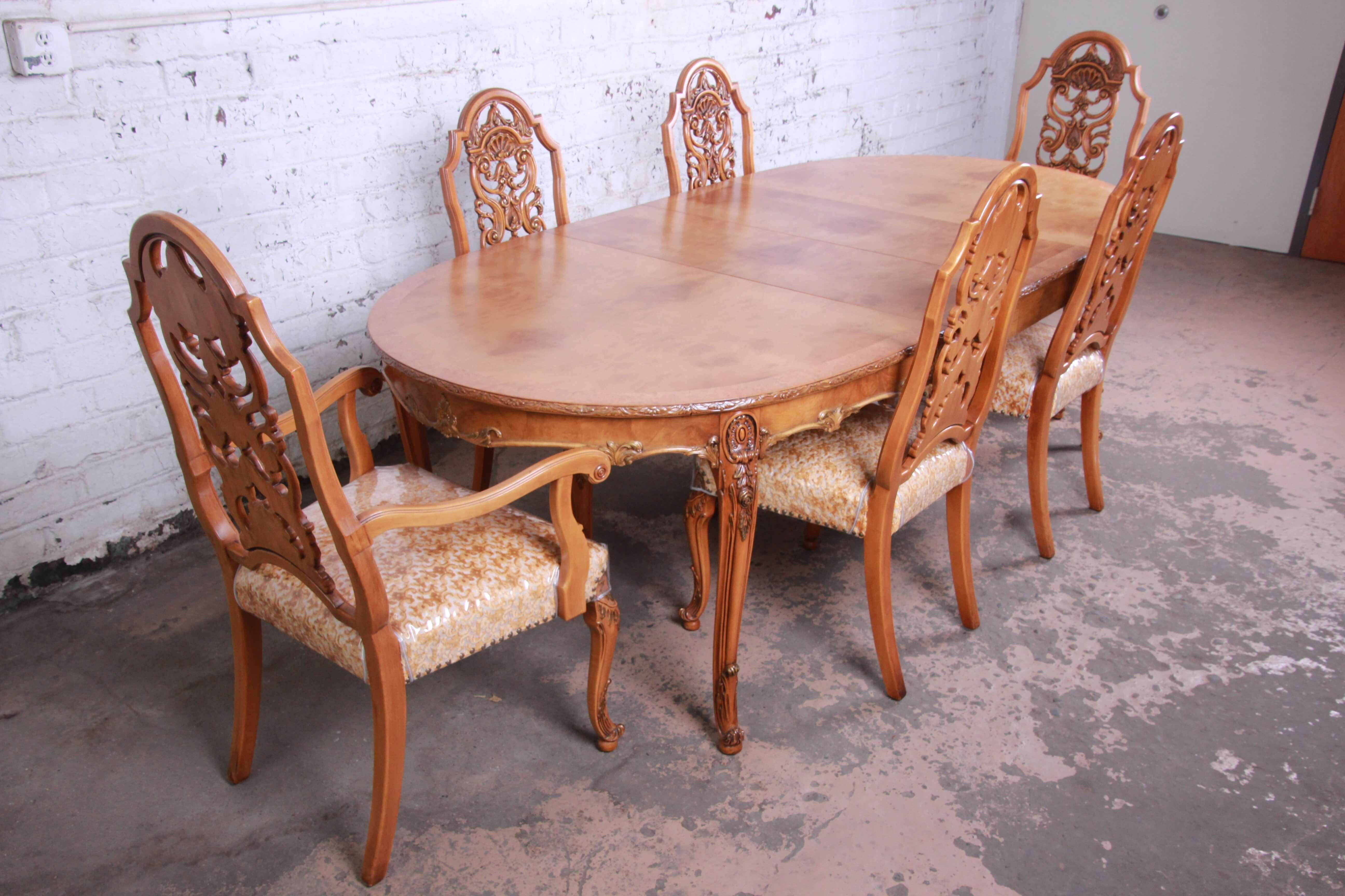Offering a stunning ornate burl wood French carved dining table and six chairs by Romweber. This newly refinished table has a banded edge and expertly bookmatched burl wood top leaving it the focal point of any important elegant space. The table has