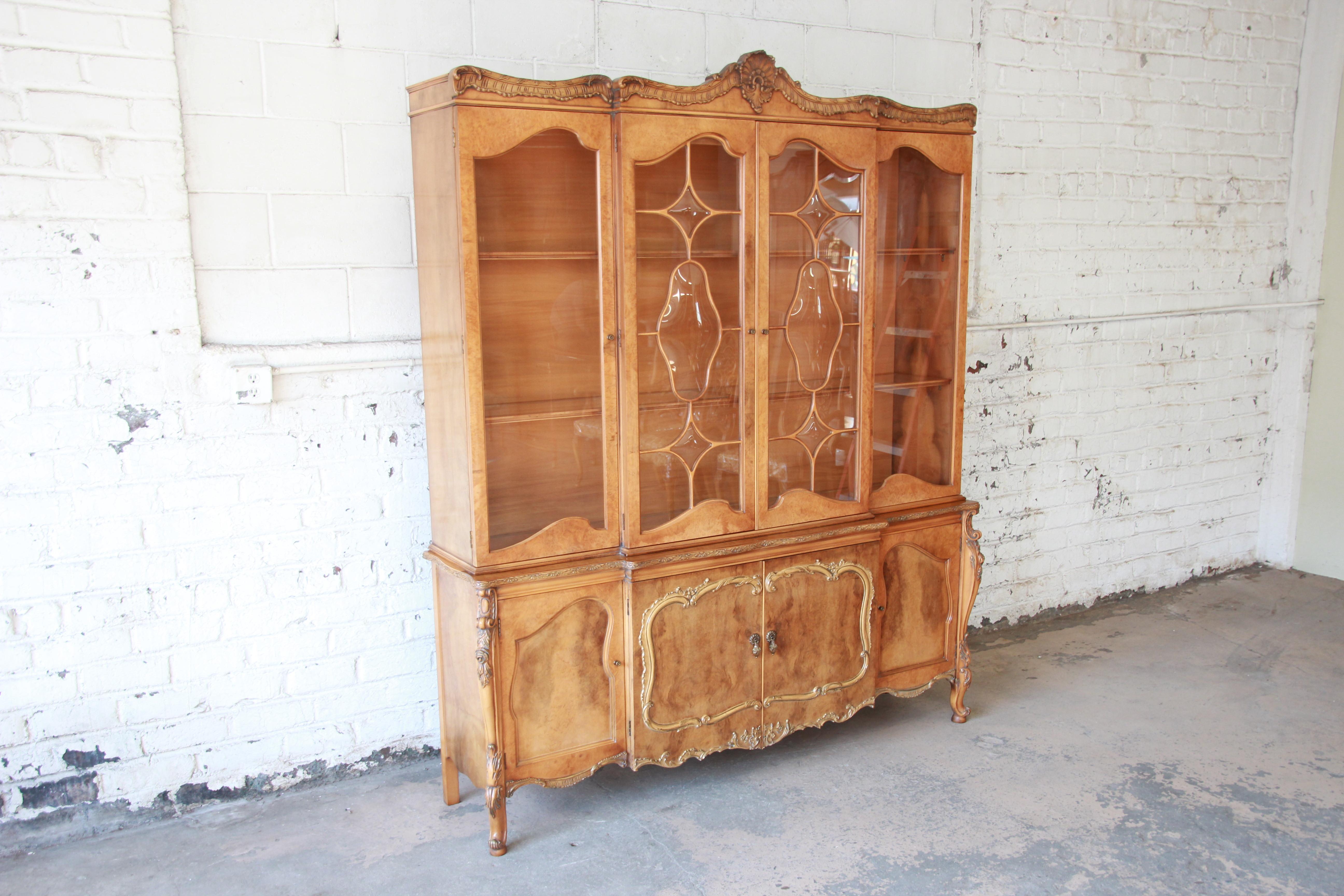 Offering an outstanding elegant Romweber burl wood French carved sideboard with hutch. The china cabinet has nice French carved details throughout the piece. The two centre bubble glass doors open up to two shelves that are shared shelves that are