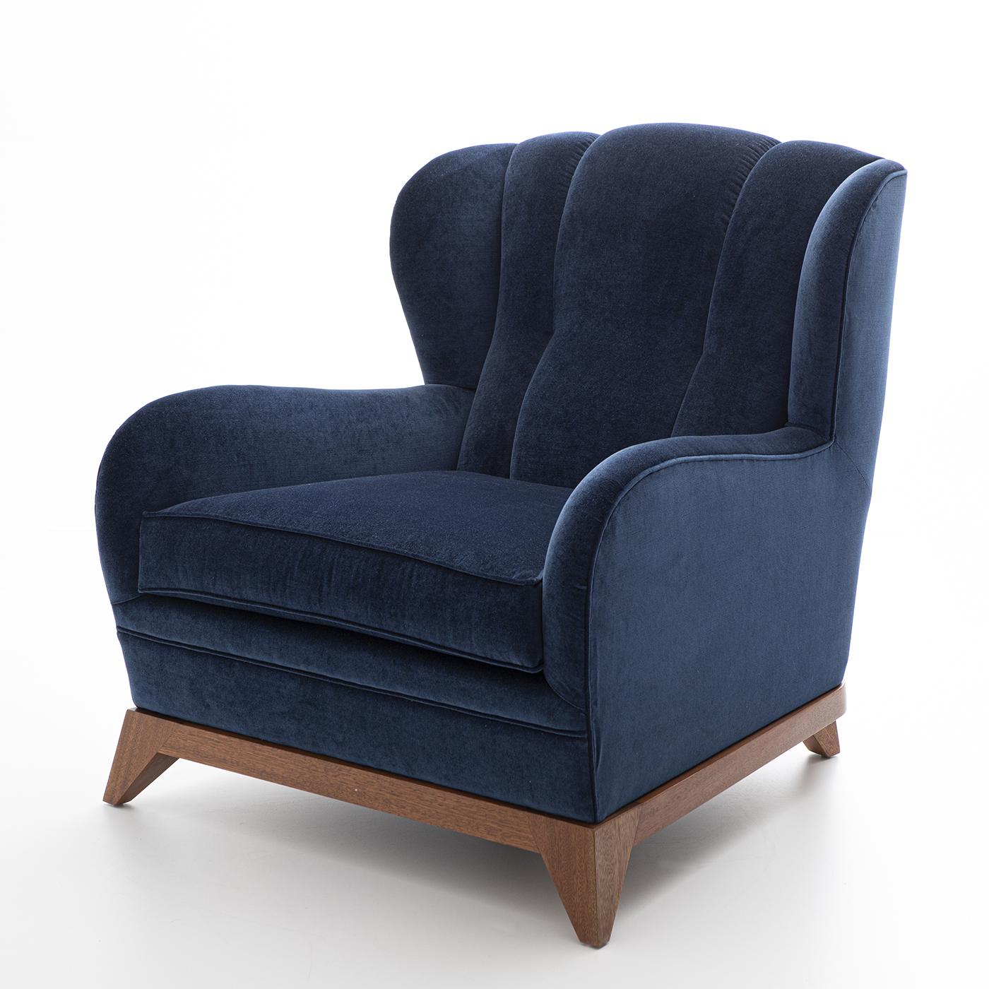 Merging smooth lines and an imposing character, this exquisite wooden armchair exudes comfort and sophistication with its inviting silhouette. Upholstered in deep-blue velvet, it features a wide backrest enlivened by a delicate channeled texture.