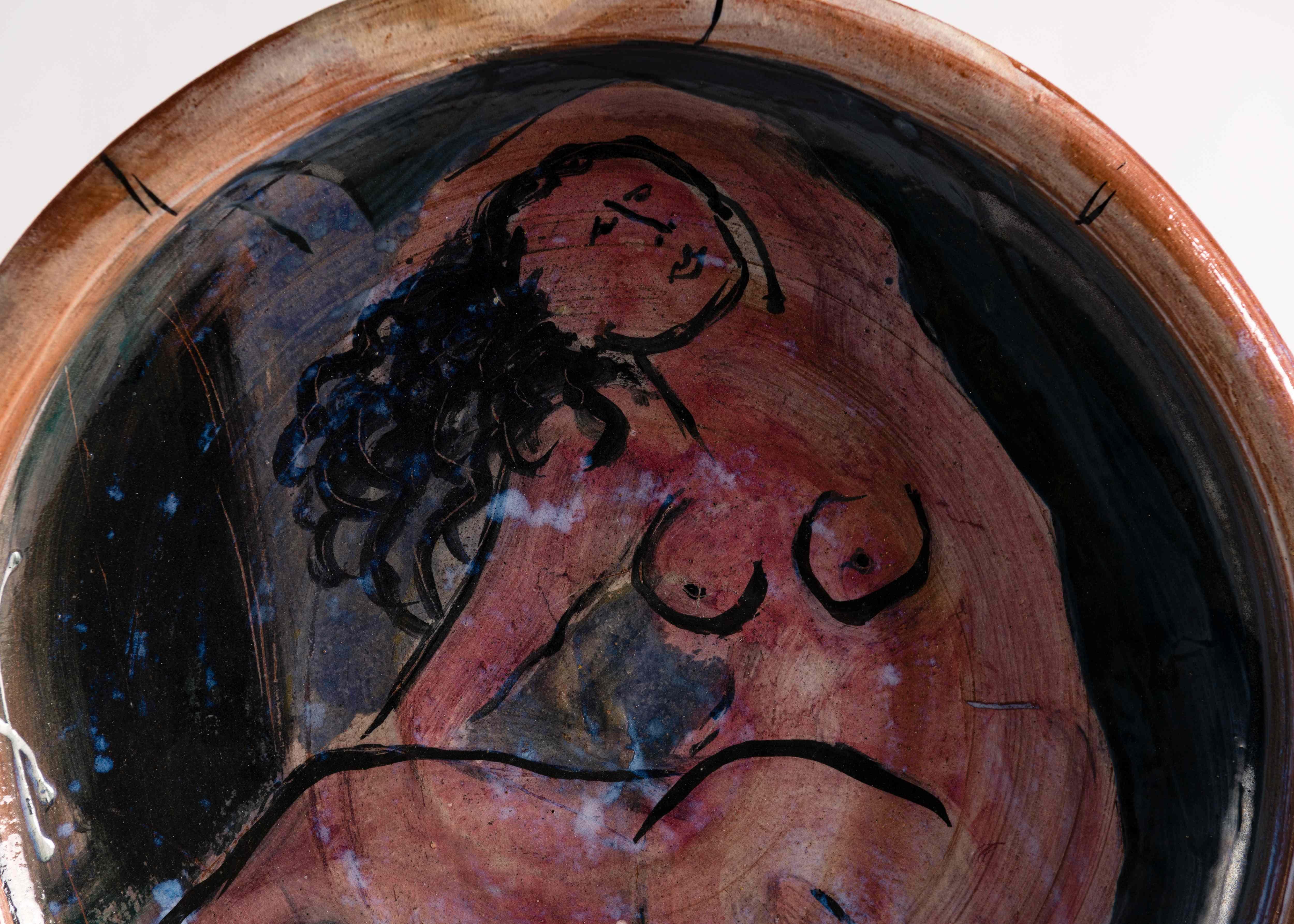 This exquisite glazed ceramic charger features a picture of a reclining nude, a clever recreation of a western subject in new terms appropriate to a work situated in its time and place. Figured roughly, and featured at the center of a decorative