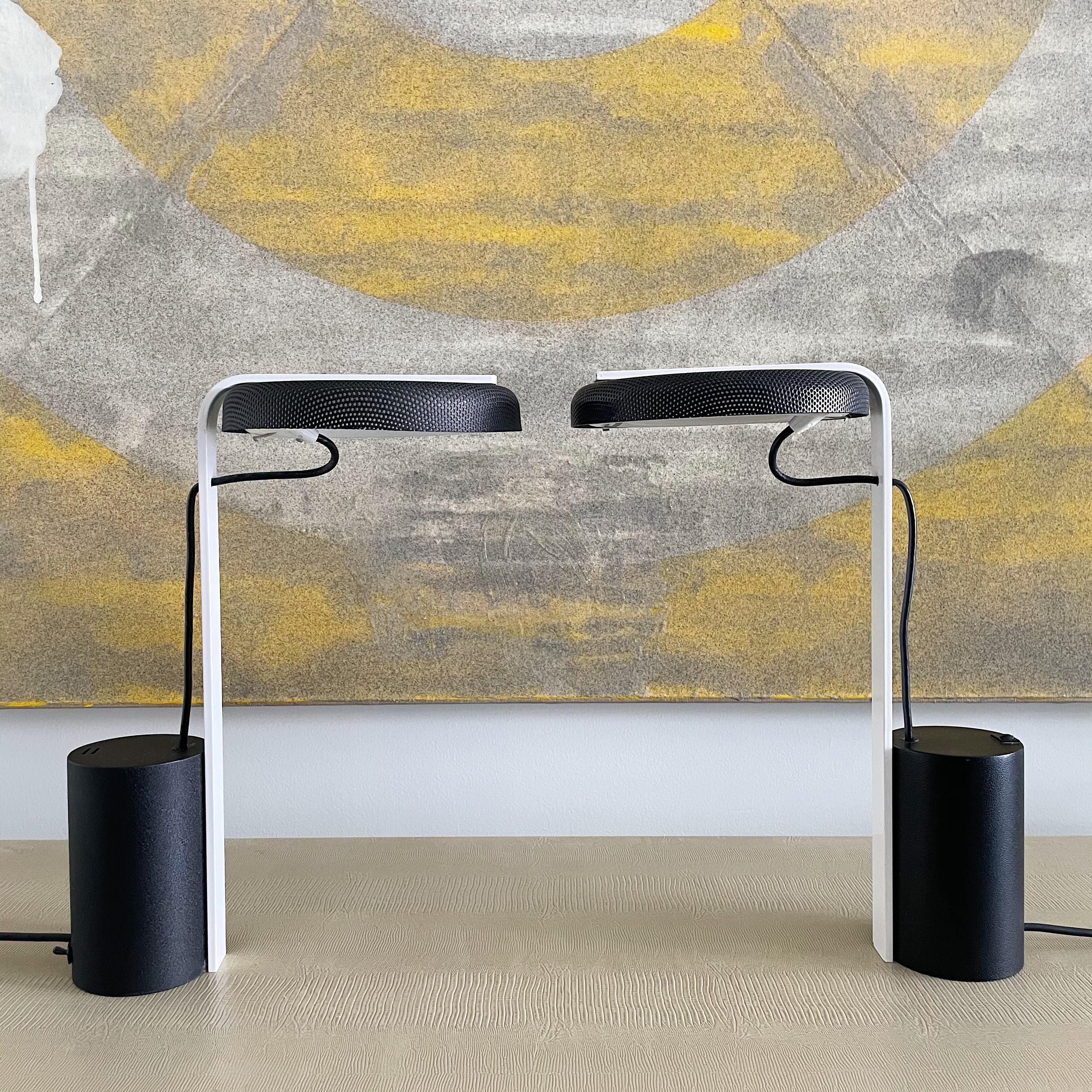 2 / 2

Offered for sale is a pair of sleek post-modern desk lamps designed by Ron Rezek. These lamps feature a counterbalance design and come with a round perforated shade in black enameled metal, a white stem, and a black cylindrical base. They