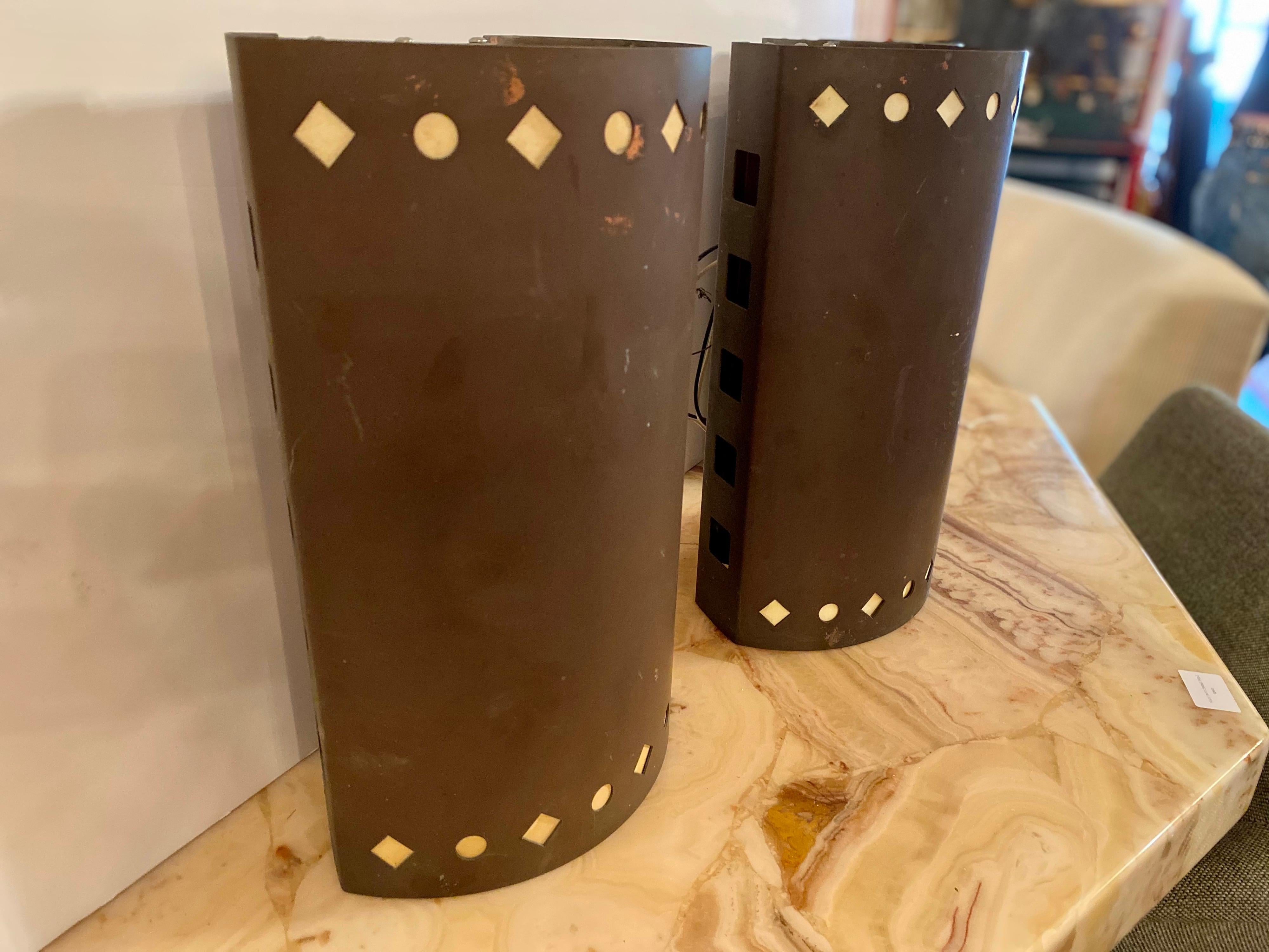 Set of three Ron Rezek copper outdoor wall sconces each pierced with geometric accents around the top and bottom of sconces. The back of each wall sconce is fabricated to attach to a wall. These vintage outdoor wall sconces are in great condition.