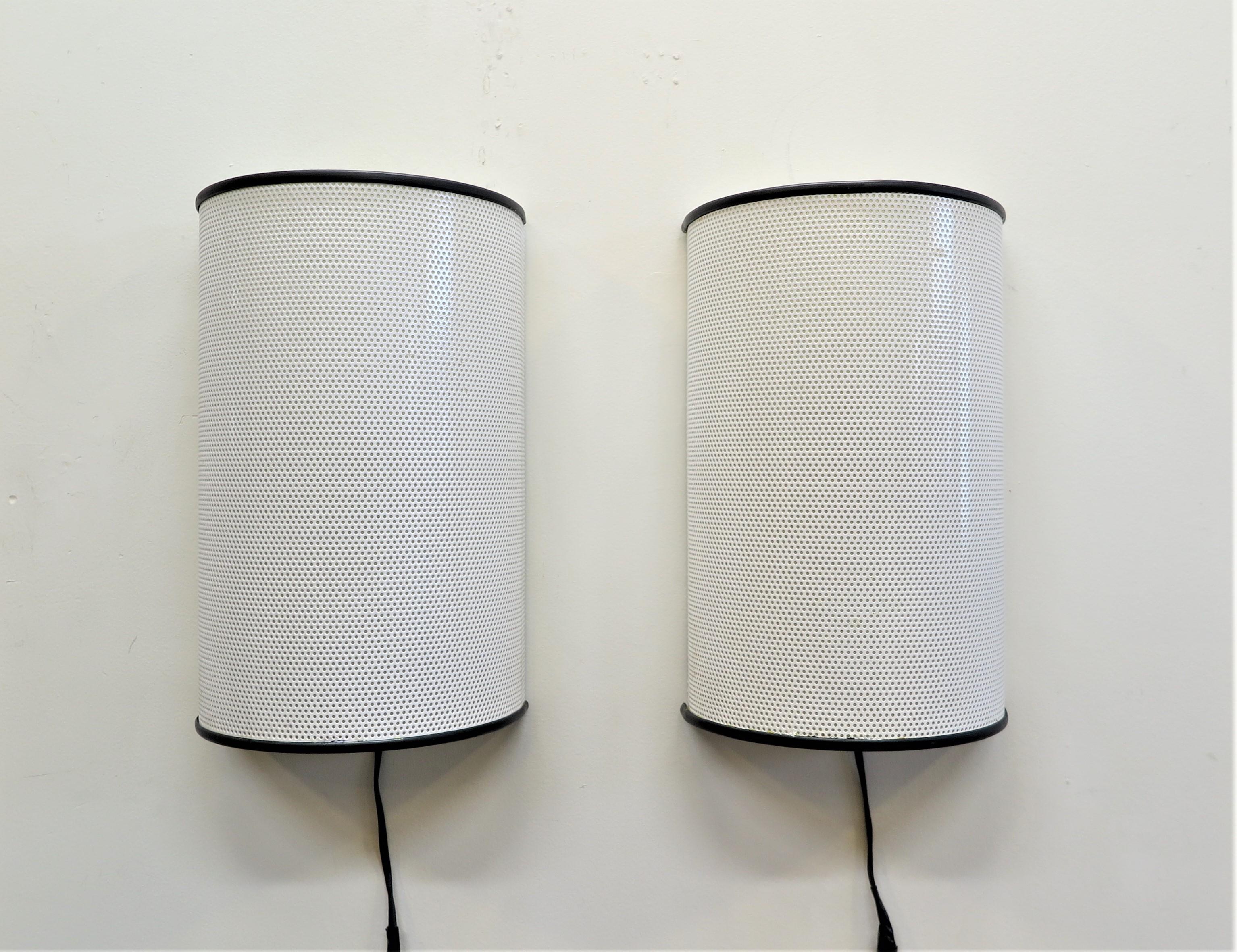 Ron Rezek for Artemide sconces. Shades are perforated white powder coated steel with black rubber trim on the rims. A plastic coating inside the shade covers the perforations and help soften the diffusion. Manufactured in 1978 one his early designs