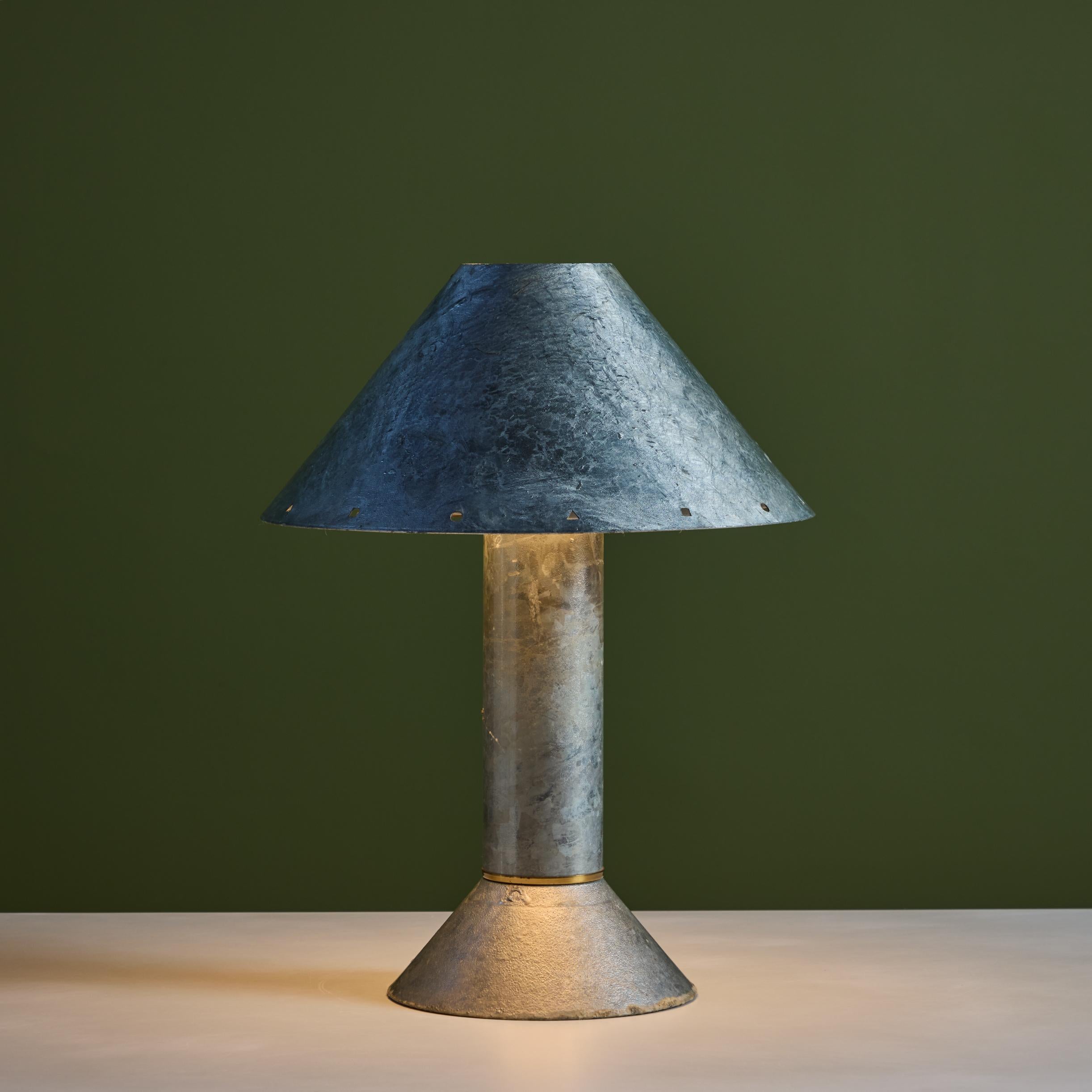 Postmodern table lamp by Los Angeles lighting designer Ron Rezek, c.1980s. The lamp features a galvanized steel frame and removable steel shade with polished brass ring accent that sits at the top of cone shaped base. The shade features different