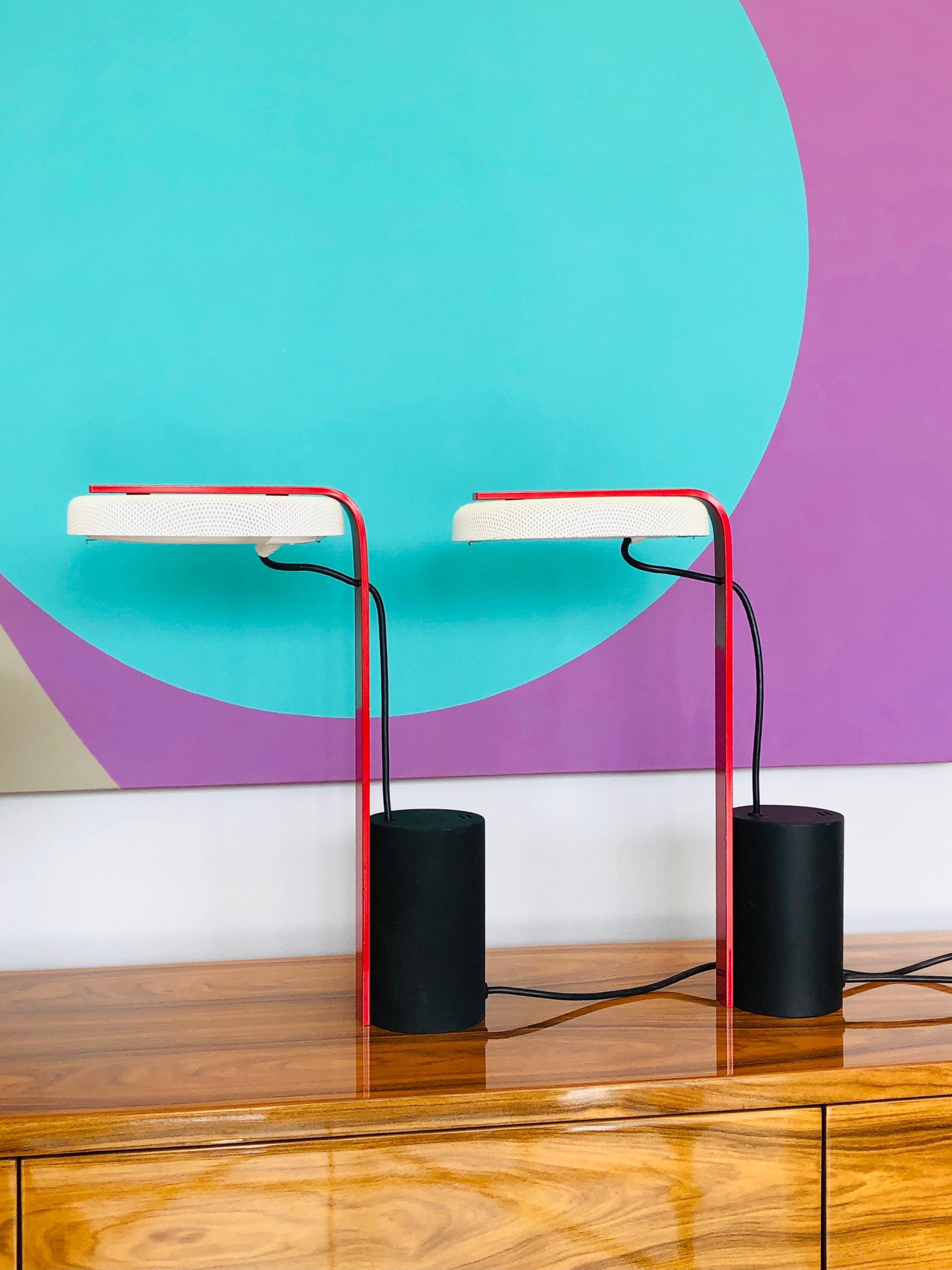 A pair of sculptural lamps by Ron Rezek, done in the post modern language, cylindrical base, long neck and round diffuser in perforated metal.