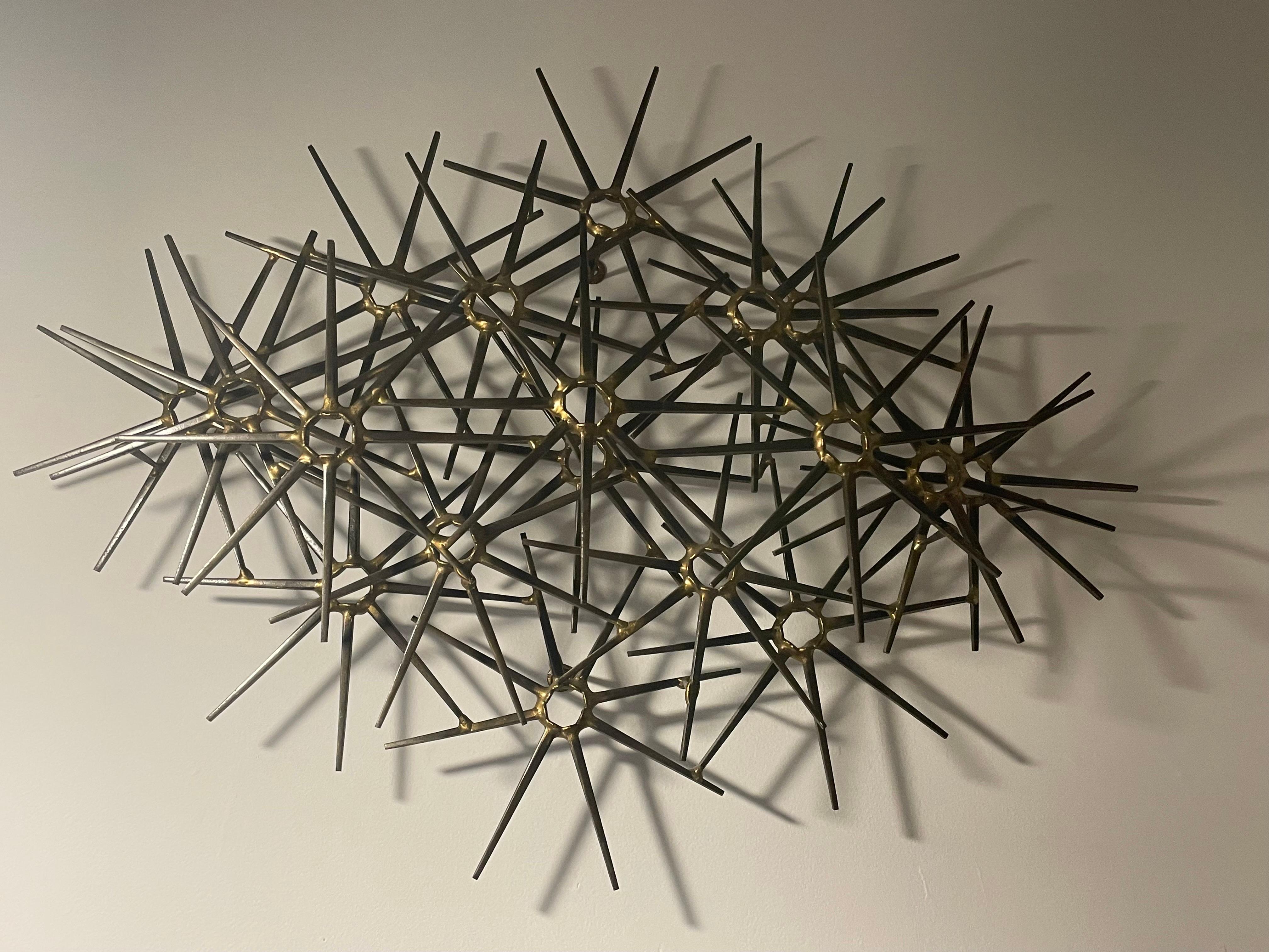 Mid-Century Modern Brutalist wall sculpture by Ron Schmidt circa 1960's. Made of cut nail, assembled and detailed with brass welding. Pinwheel pattern. Very nice condition.