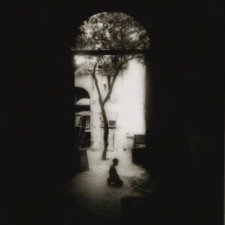 Kneeling Boy: black & white photo of Havana, Cuba w/ tree in arched doorway - Photograph by Ron Tarver