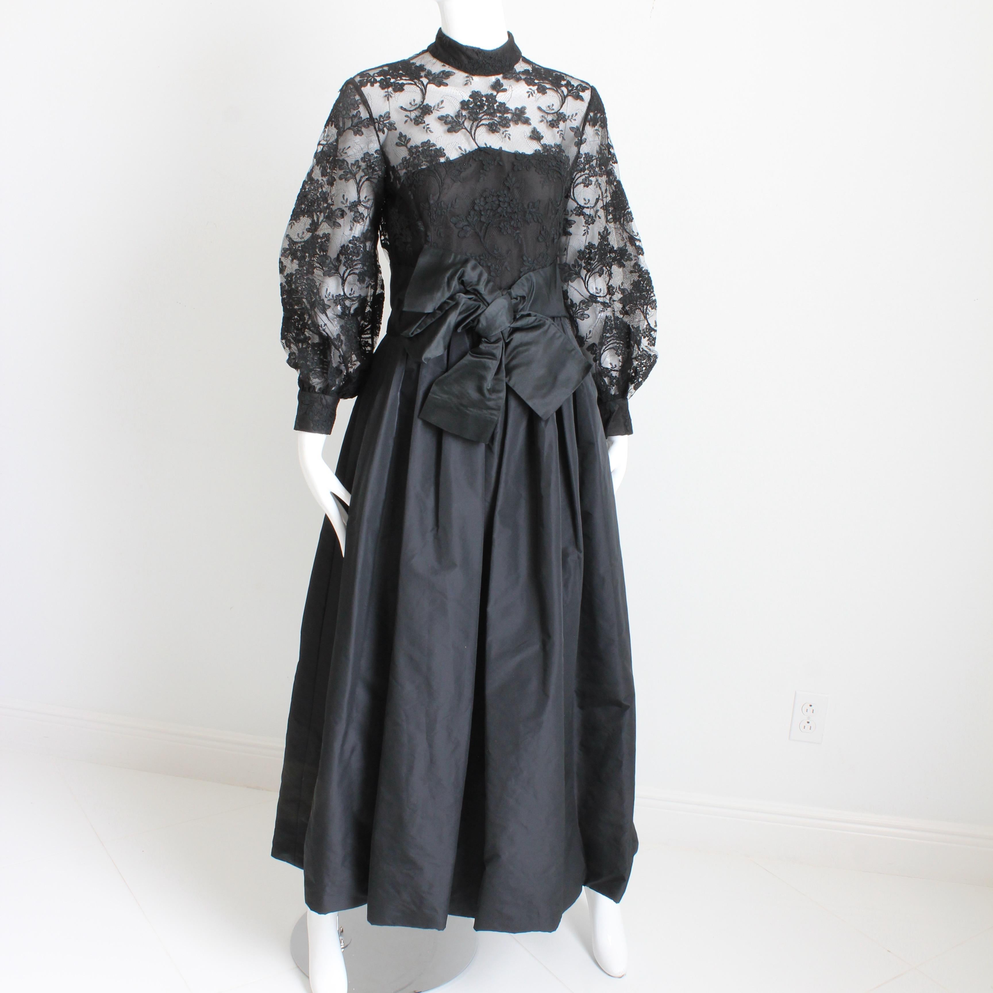 Cette robe du soir en dentelle noire et taffetas a été réalisée par Ronald Amey dans les années 1970 et est absolument magnifique.  Le corsage est orné de dentelle florale noire avec un filet en dessous, et la jupe froncée est faite de ce qui semble