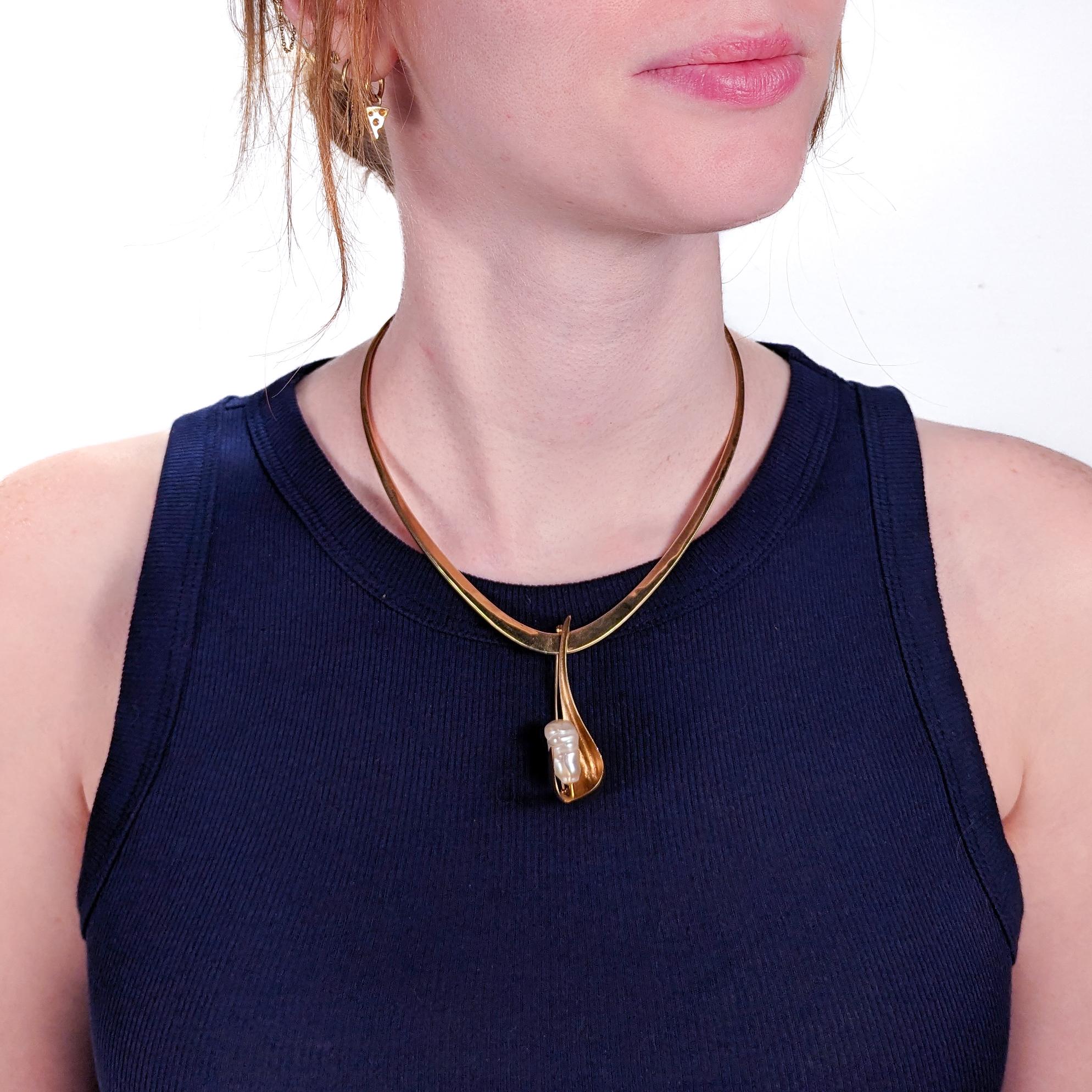 A possibly unique neckpiece and brooch parure by Ronald Hayes Pearson.

Comprised of a 14-karat forged yellow gold collar necklace together with a 14-karat forged yellow gold brooch set with a very large baroque pearl.

The reverse of the necklace