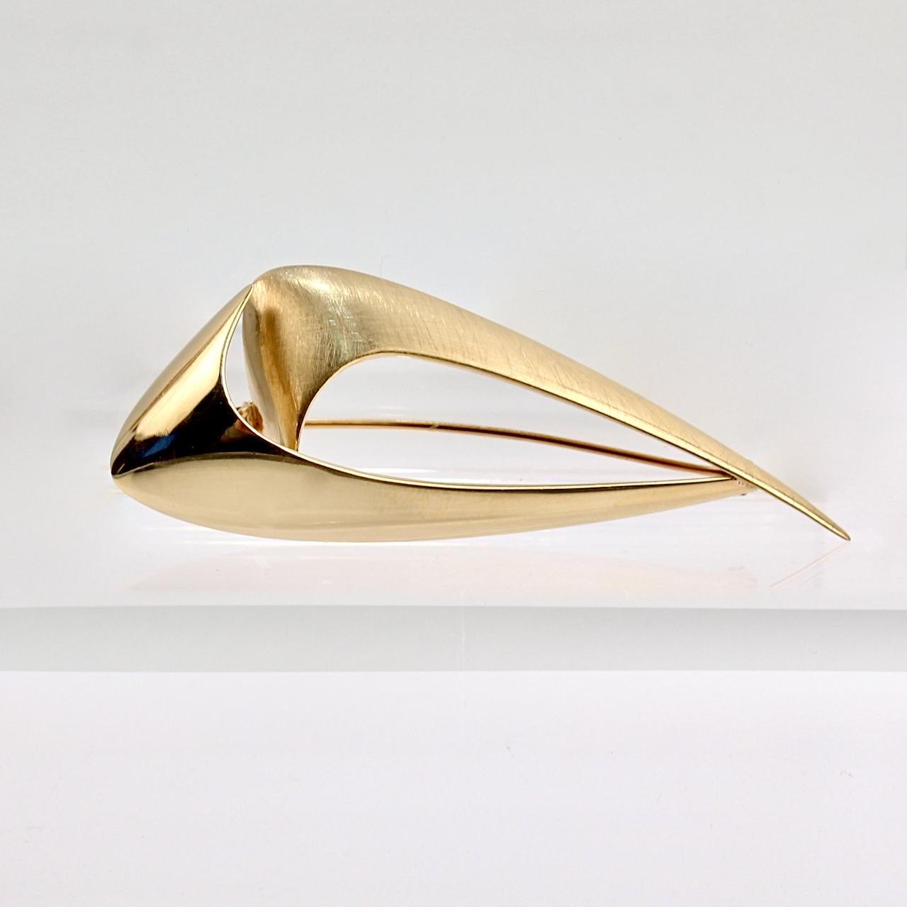 A very fine modernist brooch by Ronald Hayes Pearson. 

Comprised of 14-karat forged yellow gold and fashioned in the shape of 2 of Pearson's conjoined swooshes or checks.

One half has a brushed finish and the other has a high polish.
  
The brooch