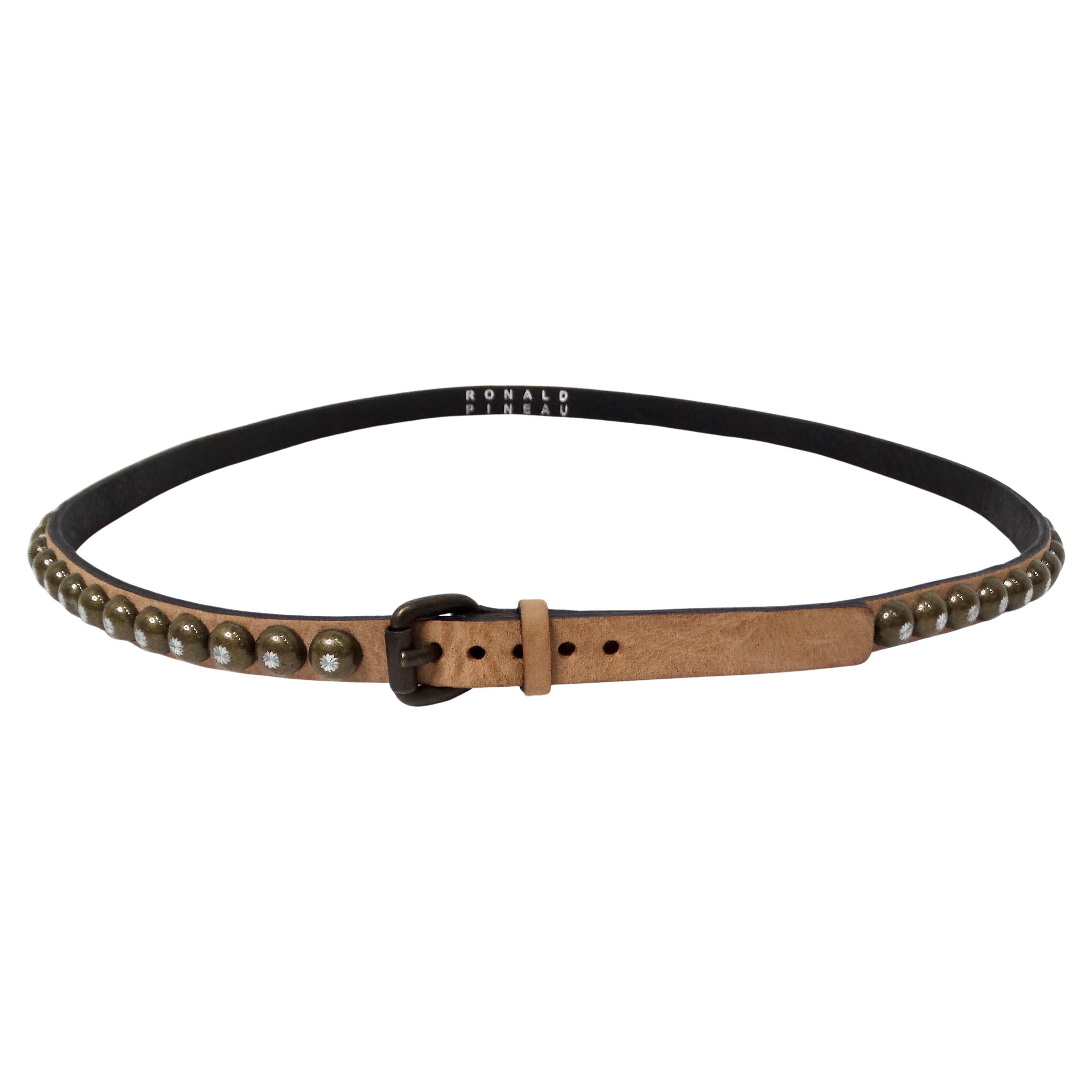 Introducing the Ronald Pineau Skinny Light Brown Brass Studded Leather Belt, a perfect blend of elegance and style that accentuates any outfit. This expertly crafted tan leather belt features polished brass studs, each adorned with a stunning
