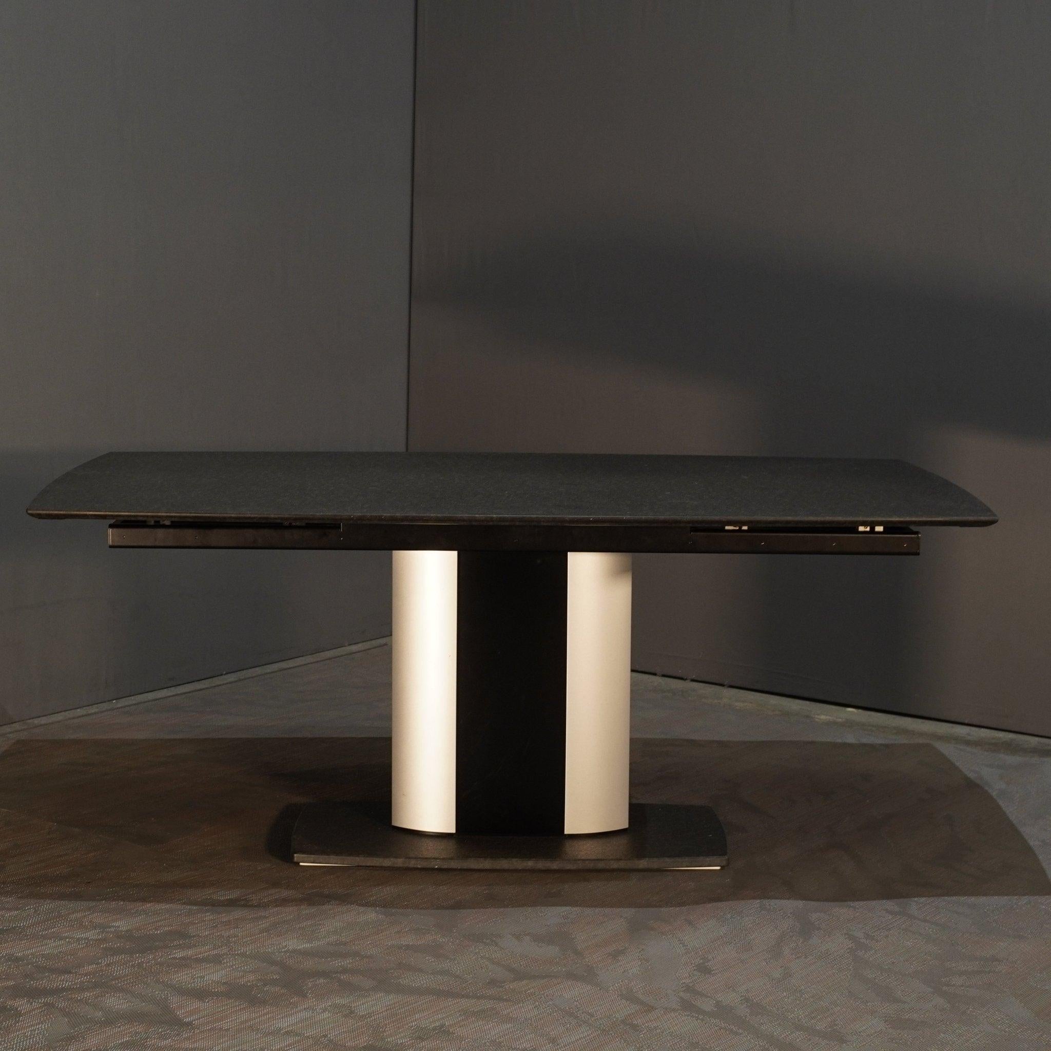 Der ausziehbare Esstisch G 2220/E, entworfen von Kurt Lenski für Ronald Schmitt, ist ein Beispiel für moderne Eleganz und innovatives Design. Die rechteckige Tischfläche mit der raffinierten schwarzen Glasplatte lässt sich mühelos erweitern und