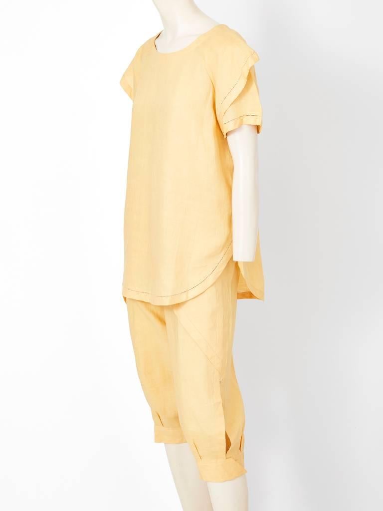 Ronaldus Shamask, butter yellow linen, tunic with with knickers ensemble. Tunic has a curved hem with faggoting detail along the hem and sleeves. Knickers have A spiral external seam with the same faggoting detail as the tunic.
