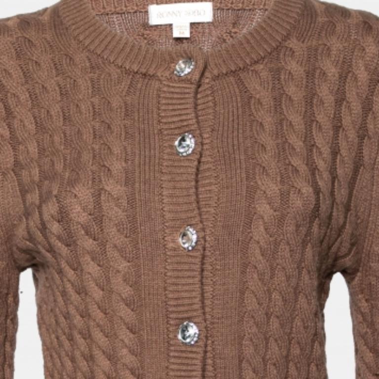 Ce charmant cardigan marron de Ronny Kobo est magnifiquement cousu en laine dans un motif tricoté en câble. Cette pièce confortable s'orne de boutons sur le devant. Associez ce cardigan à manches longues à un jean ou une jupe pour un look chic.