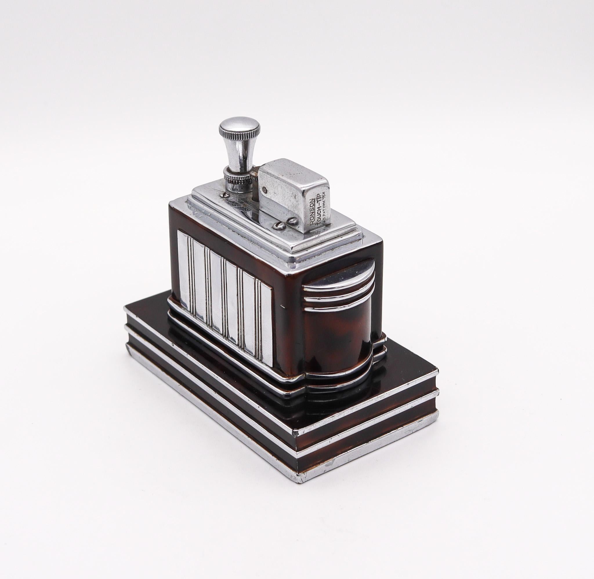 Ein von Ronson entworfenes Deluxe-Schreibtischfeuerzeug.

Dieses äußerst seltene Ronson Deluxe Classic Touch-Tip Feuerzeug wurde 1938 von der Ronson Art Metal Works Inc. in Newark, New Jersey in den Vereinigten Staaten hergestellt. Mit diesem