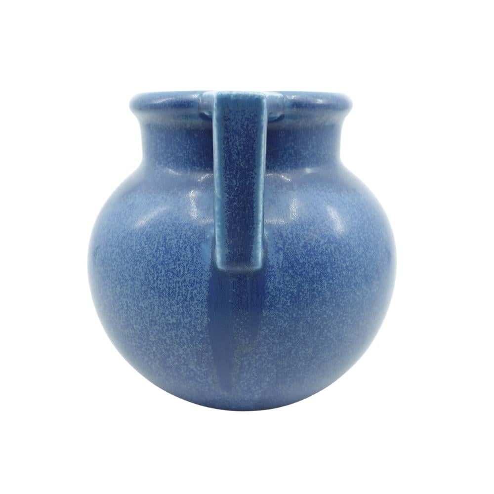 Offering this substantial hand glazed Rookwood pottery vase featuring a double handle design on a bulbous body with a cylindrical neck. This vase is has a gorgeous medium to dark blue glaze with lighter colored speckling. Vase is marked by the