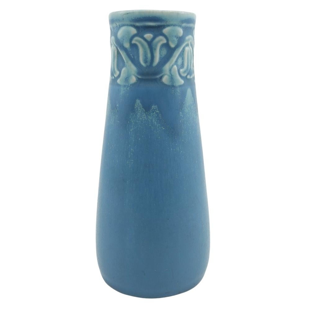 Wir bieten diese handglasierte Vase von Rookwood an, die ein eingeschnittenes, stilisiertes Blumendesign auf einem sich verjüngenden zylindrischen Körper aufweist. Diese Vase hat eine wunderschöne hellblaue Glasur mit hellerem Faden. Die Vase trägt