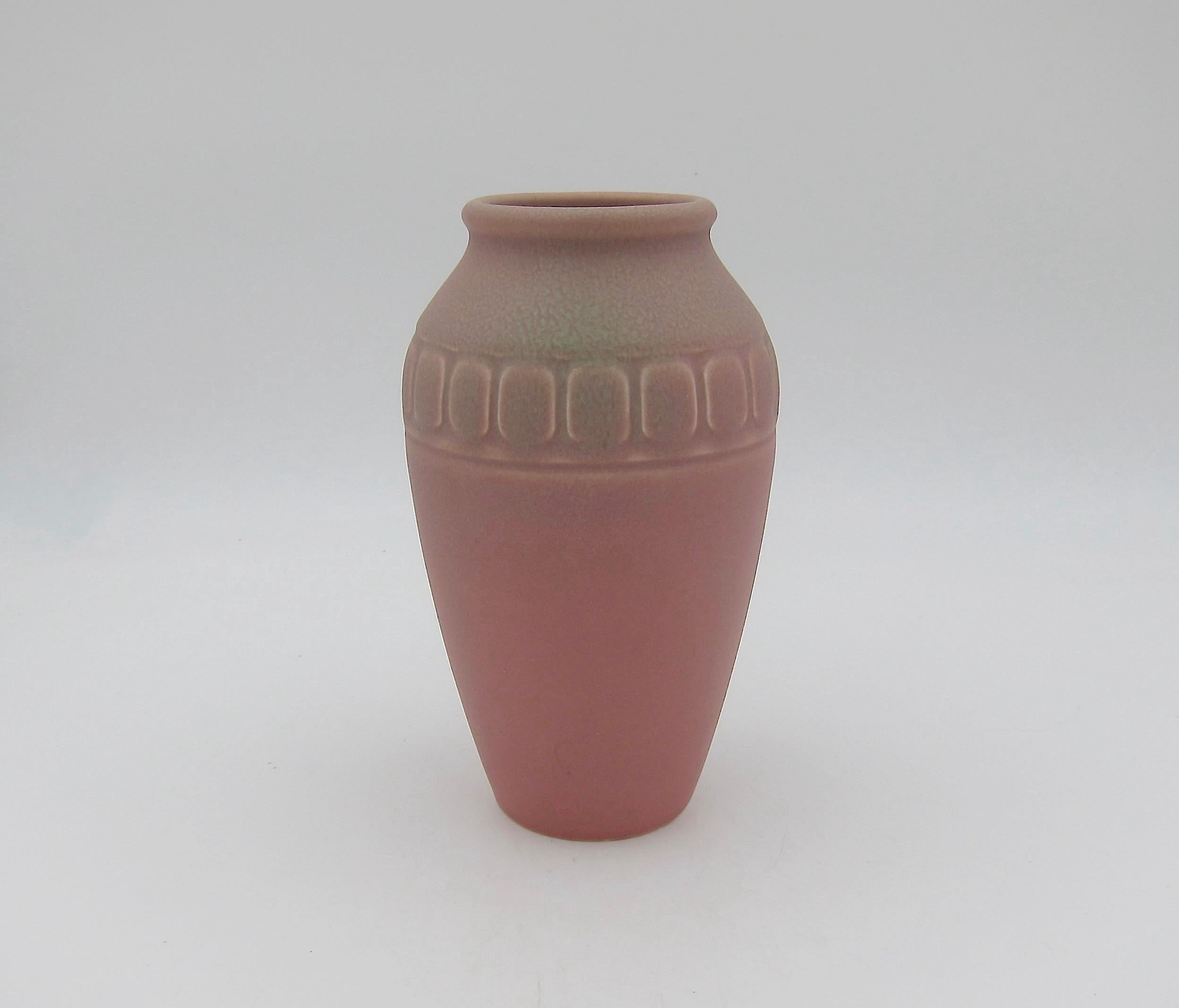 A vintage Rookwood Pottery vase date marked 1926. The American art pottery Arts & Crafts production vase is decorated with an artistic matte glaze of a velvety dusty rose-pink with mottled accents of pale green around the mouth, rim, and
