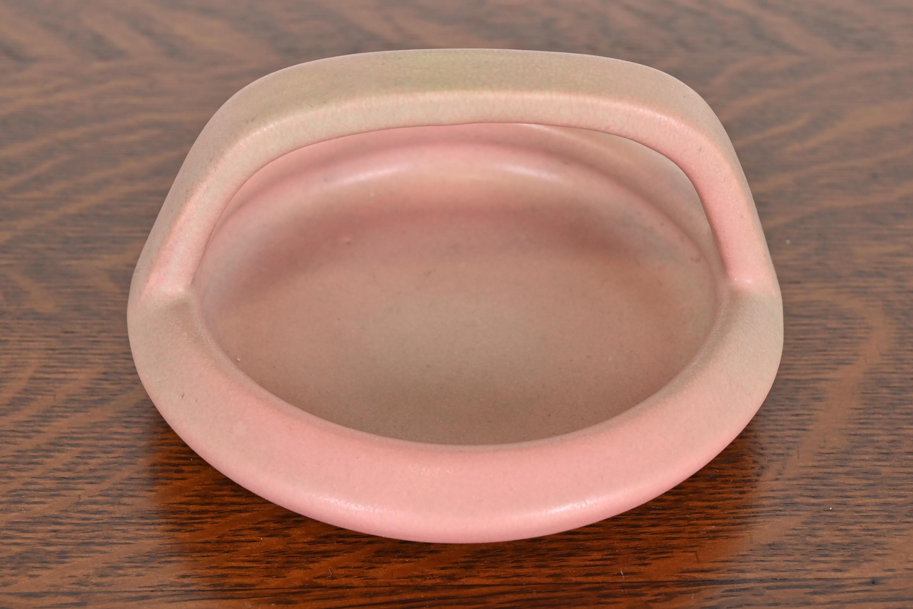 A gorgeous Arts & Crafts period glazed ceramic art pottery handled bowl, catchall, or ashtray

By Rookwood Pottery

USA, 1919

Glazed ceramic, in a beautiful pink color.

Measures: 5.63