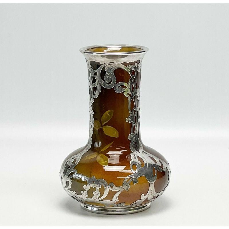 Rookwood Pottery & Gorham sterling silver overlay vase by Olga Geneva Reed, 1893

Rookwood glazed pottery and Gorham sterling silver overlay vase by Olga Geneva Reed, 1893. Green, brown, and yellow vase with leaves and flower decoration. Sterling