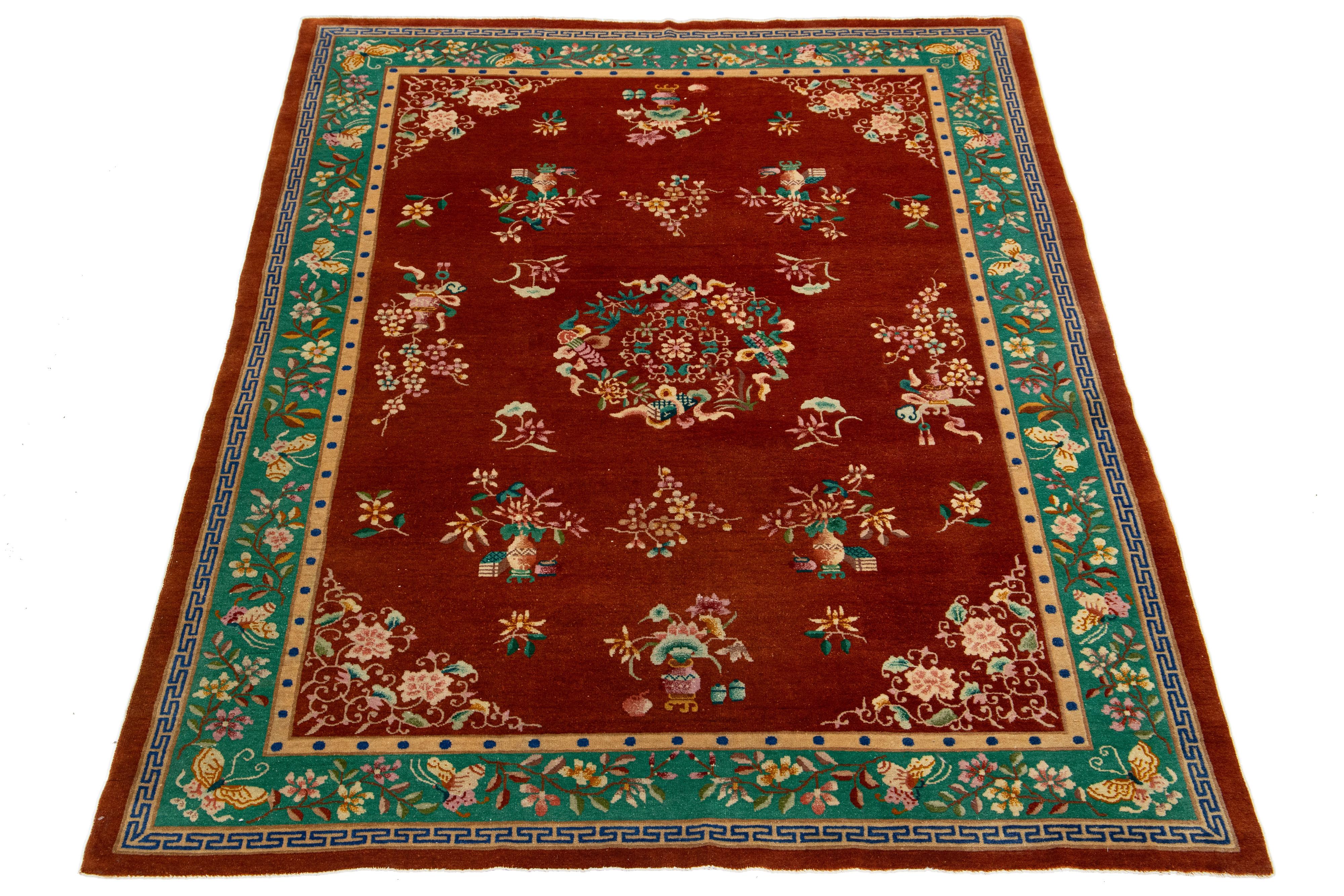 Esta elegante alfombra china antigua de lana Art Decó presenta un campo de color terracota oscuro con un borde decorativo en verde y acentos vibrantes, mostrando un impresionante motivo chino clásico.

Esta alfombra mide 6'9 x 9'7
