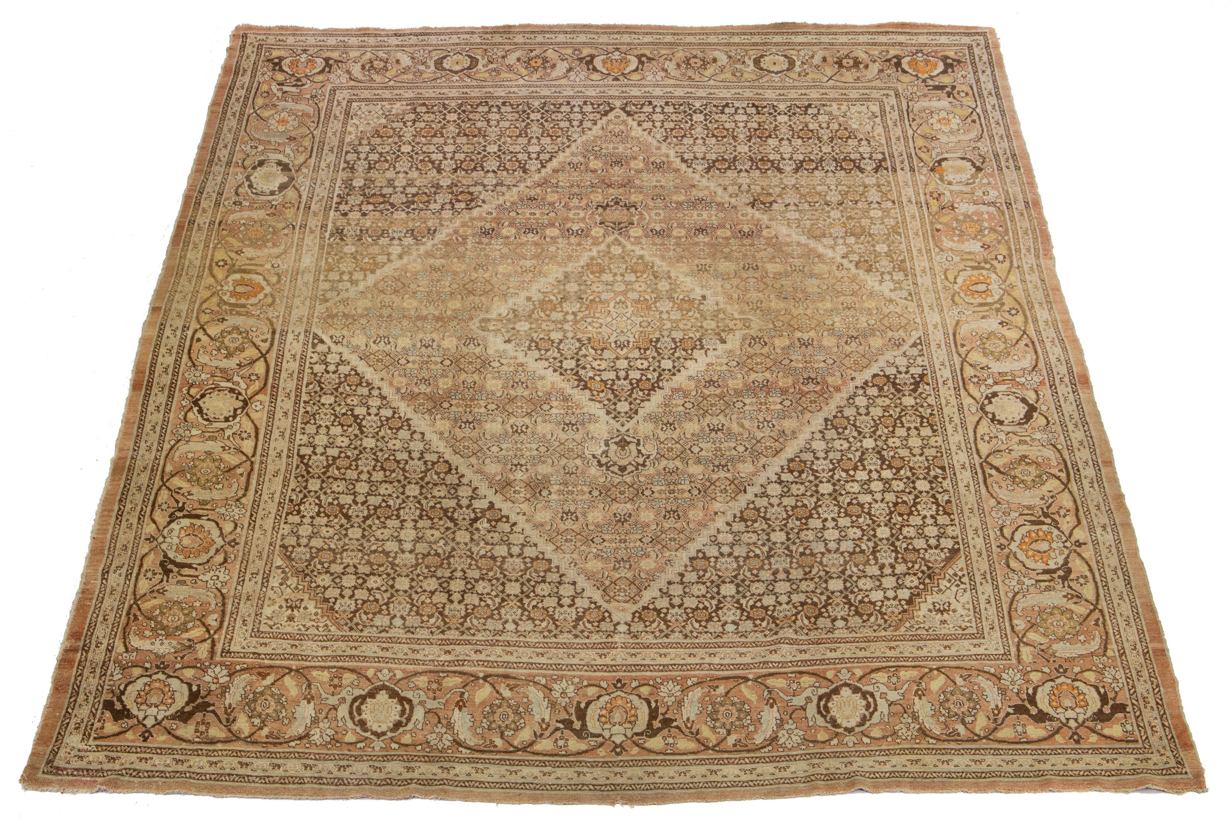 Questo tappeto persiano in lana Tabriz vanta un classico motivo floreale all-over nei toni dell'arancio, del pesca, del grigio e del beige su uno sfondo marrone. Presenta una miscela armoniosa di tonalità accattivanti, tra cui arancio, pesca, grigio