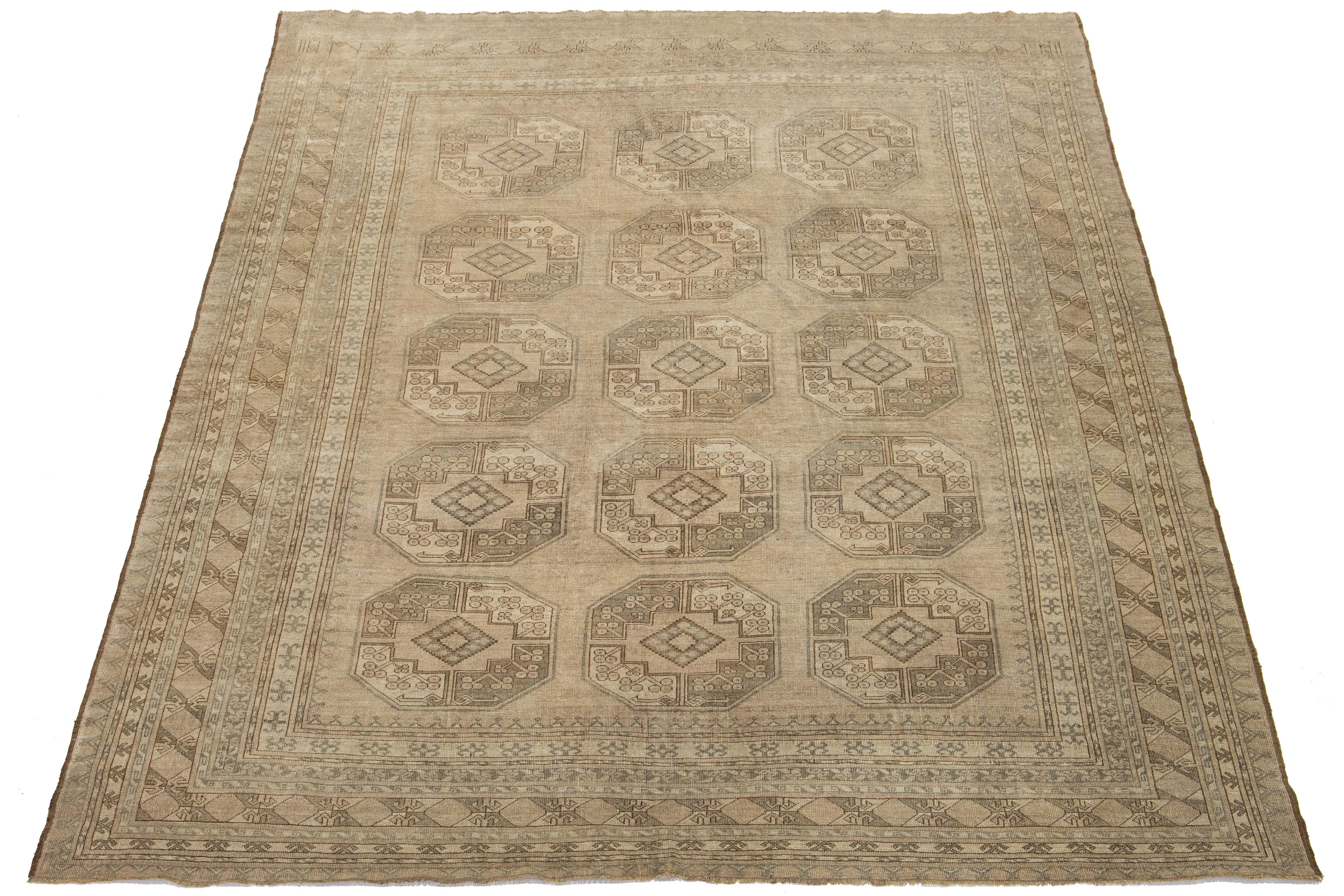 Antiker Room Size Turkmenischer handgeknüpfter Wollteppich mit einem zeitlosen beigen Farbfeld. Dieses persische Meisterwerk zeigt ein atemberaubendes Gul-Muster, das in satten Braun- und leuchtenden Grautönen aufwändig gewebt ist.

Dieser Teppich