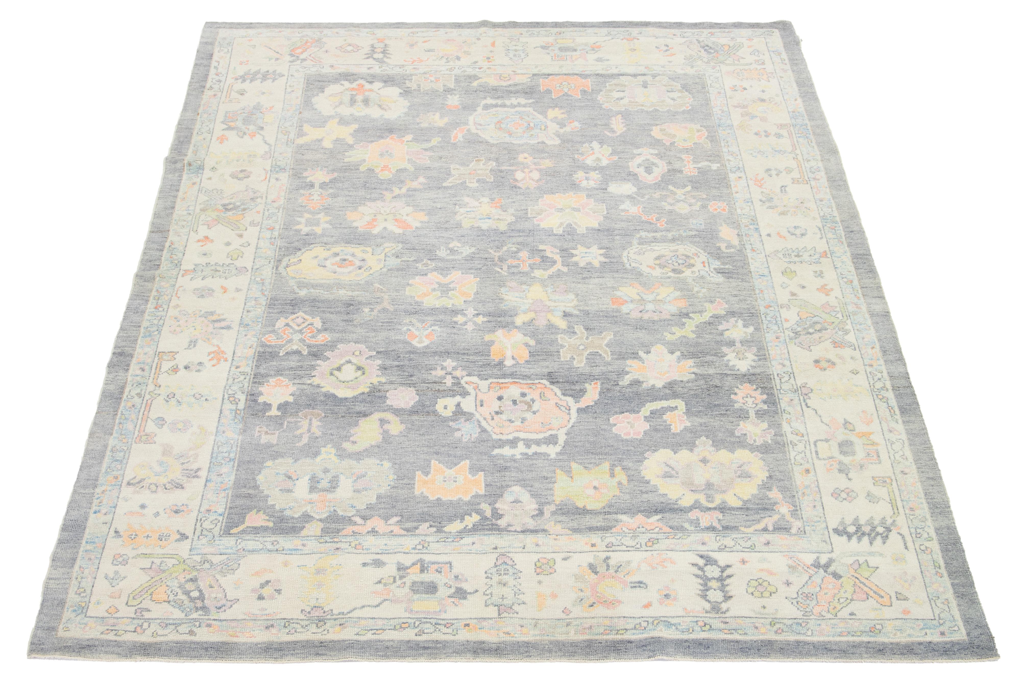 Esta moderna alfombra turca de lana anudada a mano presenta audazmente un fondo gris con un cautivador motivo floral multicolor.

Esta alfombra mide 10'2