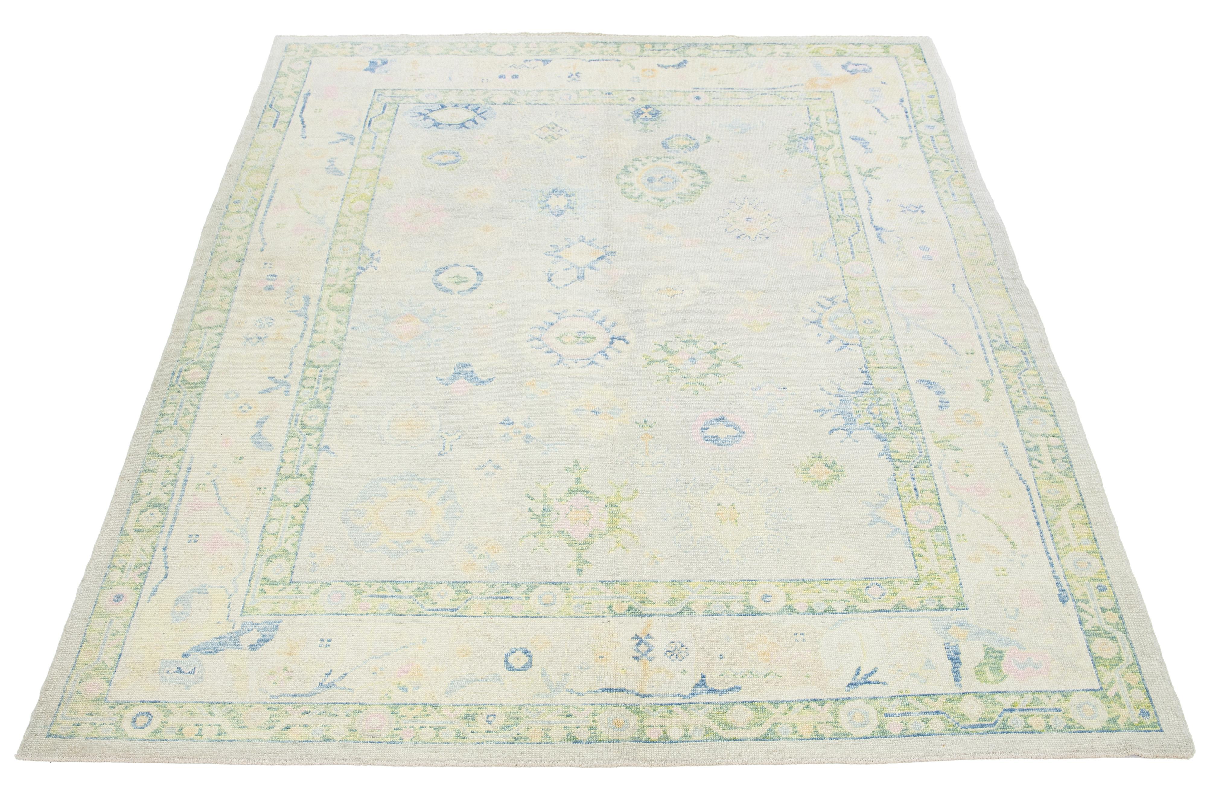 This modern Turkish hand-knotted wool rug features a beige field with a captivating blue, green, and yellow floral pattern.

This rug measures 9'6