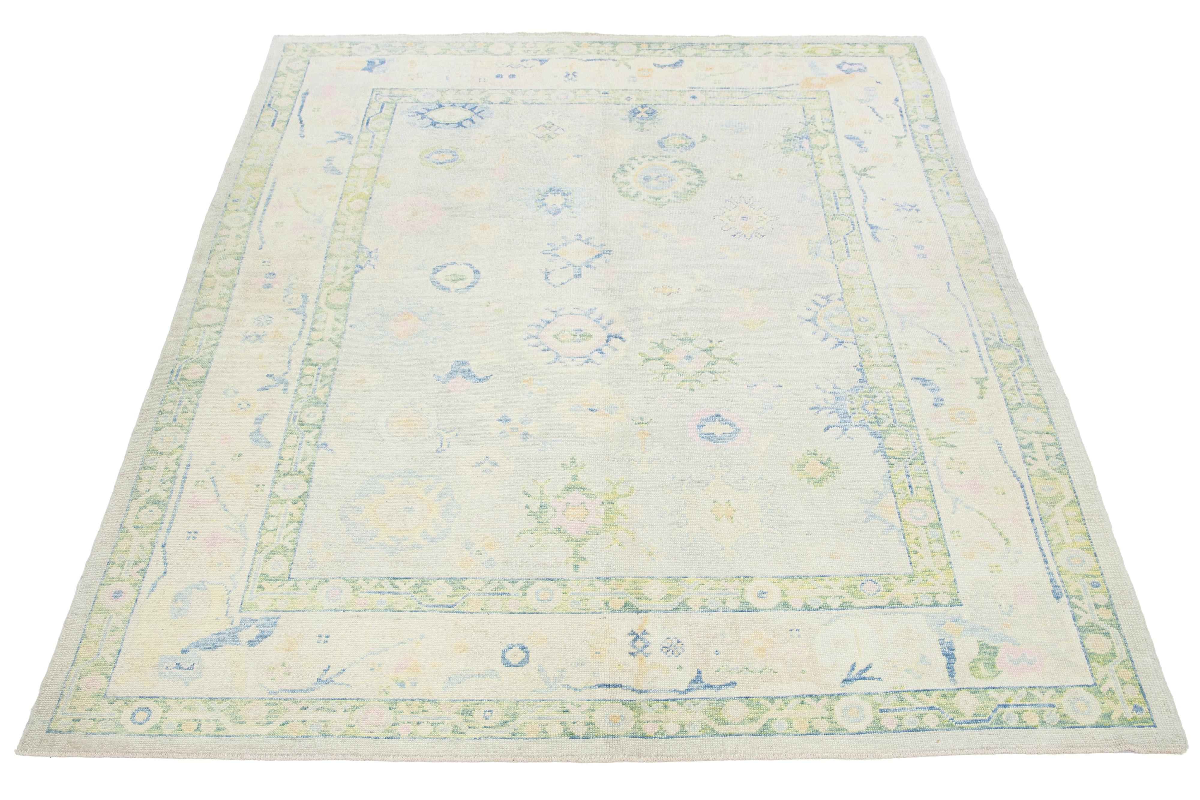 Ce tapis turc moderne en laine nouée à la main présente un champ beige avec un motif floral captivant bleu, vert et jaune.

Ce tapis mesure 9'6