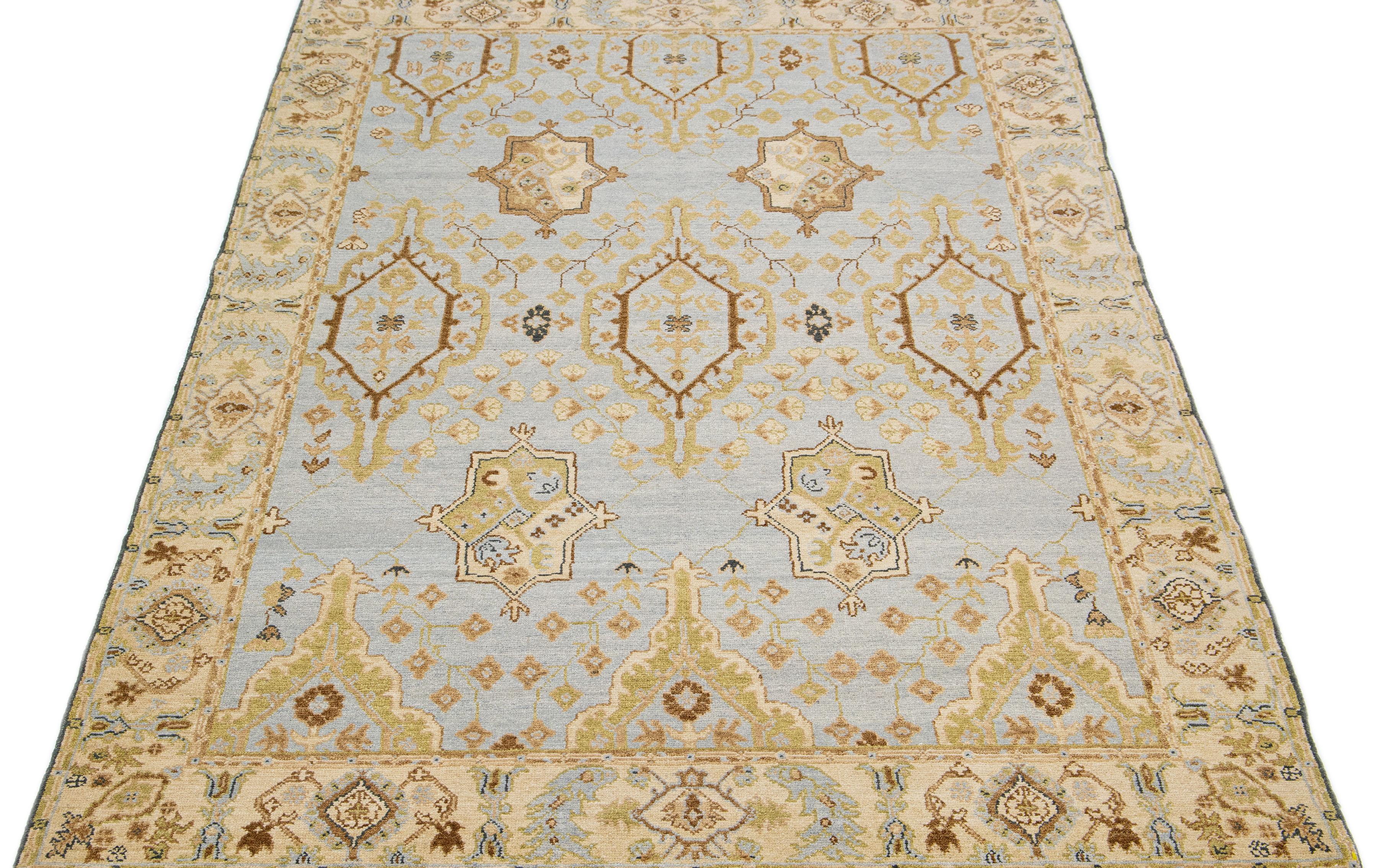 This stunning Turkish Oushak rug boasts a contemporary aesthetic, featuring a light gray field adorned with a geometric pattern that extends throughout the entirety of the piece. Complete with a beige frame and tasteful brown accents; it showcases