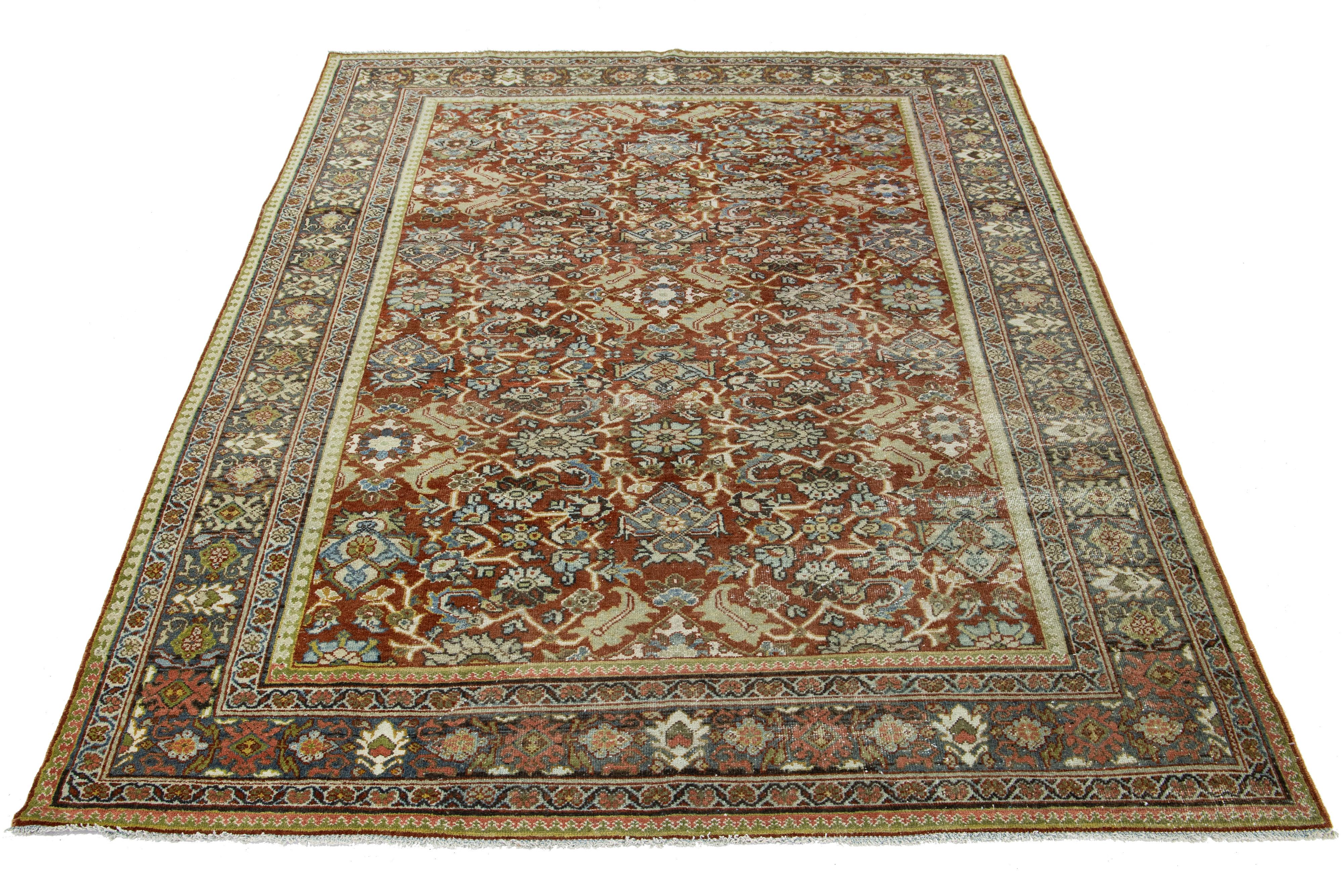 Beautiful Antique Mahal hand-knotted wool rug with a rust field. The floral motif of this Persian rug is adorned with blue, pink, and brown hues.

This rug measures 7'2