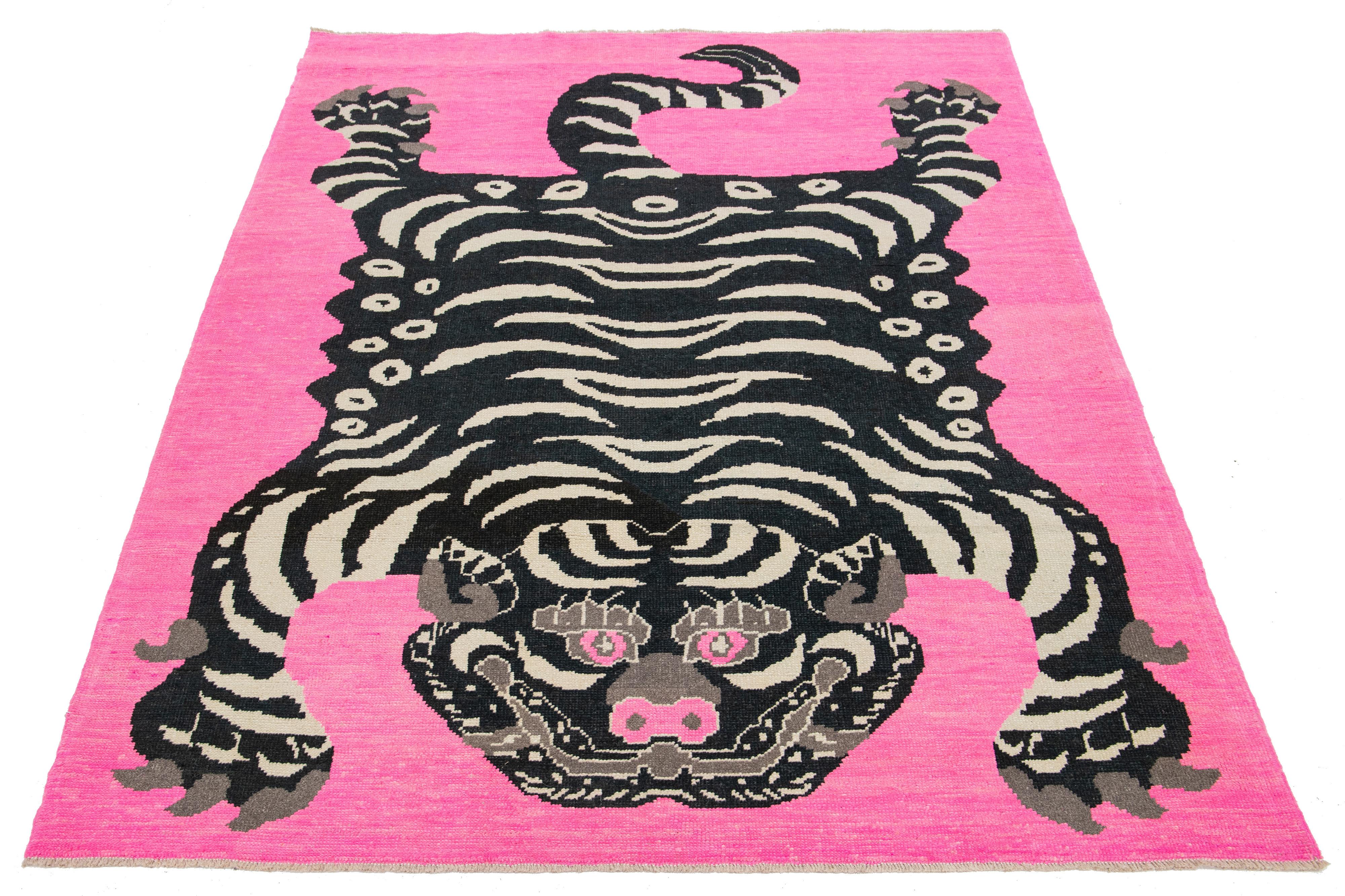This room-size wool rug from Turkey showcases a stunning tiger pictorial design with a pink backdrop and accents in black and beige. It is meticulously handmade with attention to detail.

This rug measures 7'1