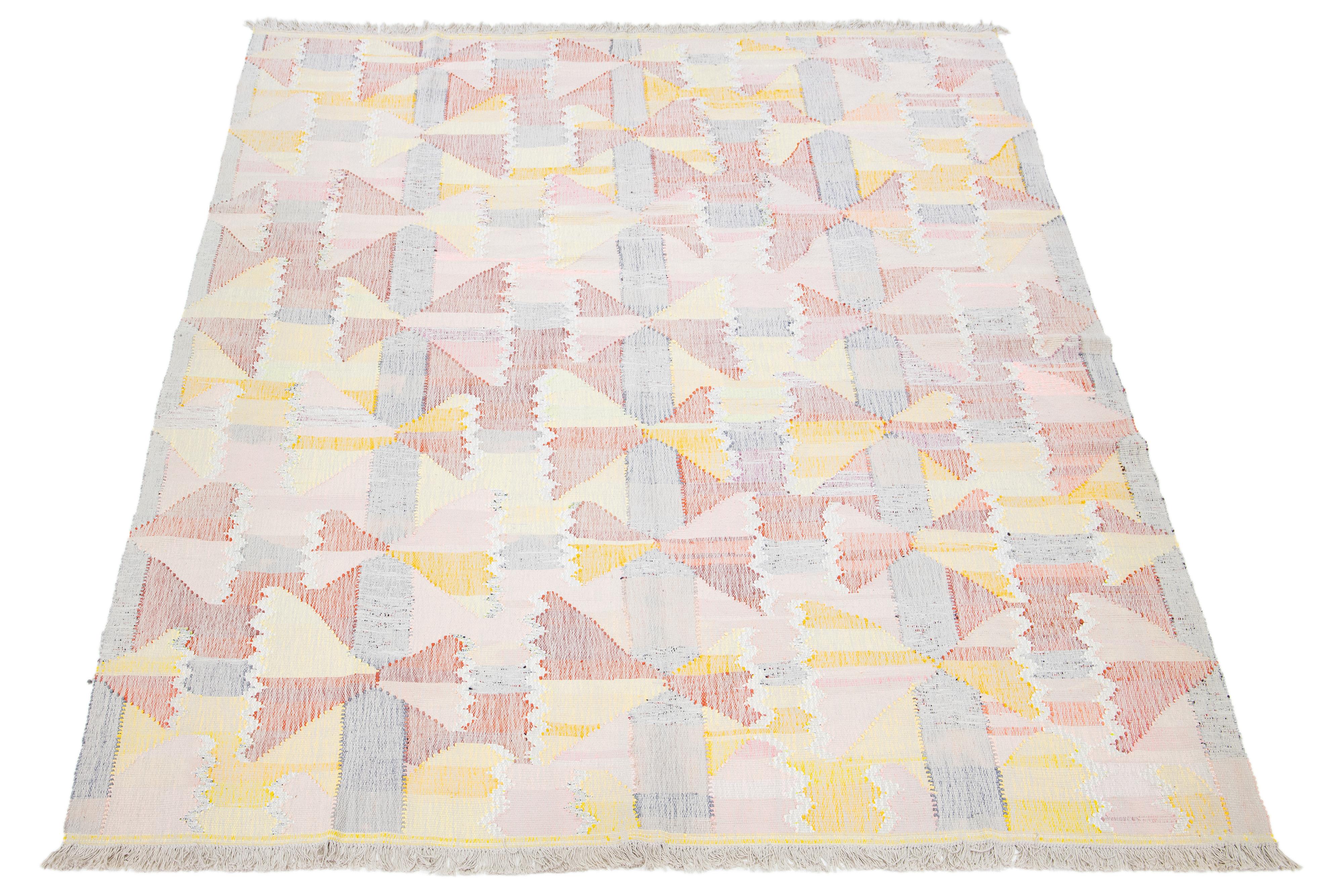 Dieser Teppich zeigt ein modernes Kelim-Flachgewebedesign aus Wolle mit einem mehrfarbigen Grundton und einem abstrakten Motiv.

Dieser Teppich misst 10' x 12'9