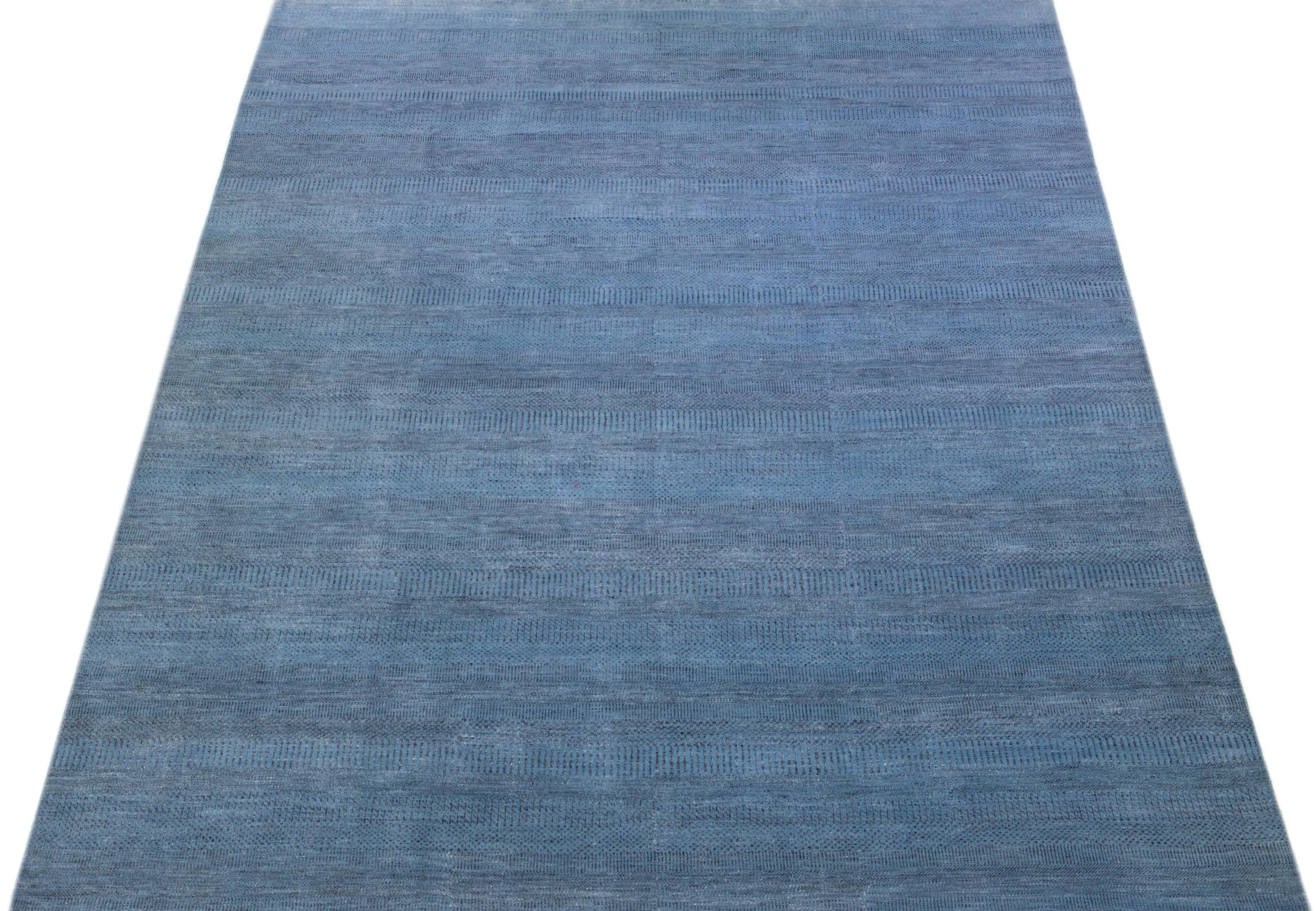 This elegant hand knotted rug is made of wool and features a subtle blue color scheme accented by an all-over geometric pattern—an ideal addition to any contemporary interior.

This rug measures 9'11