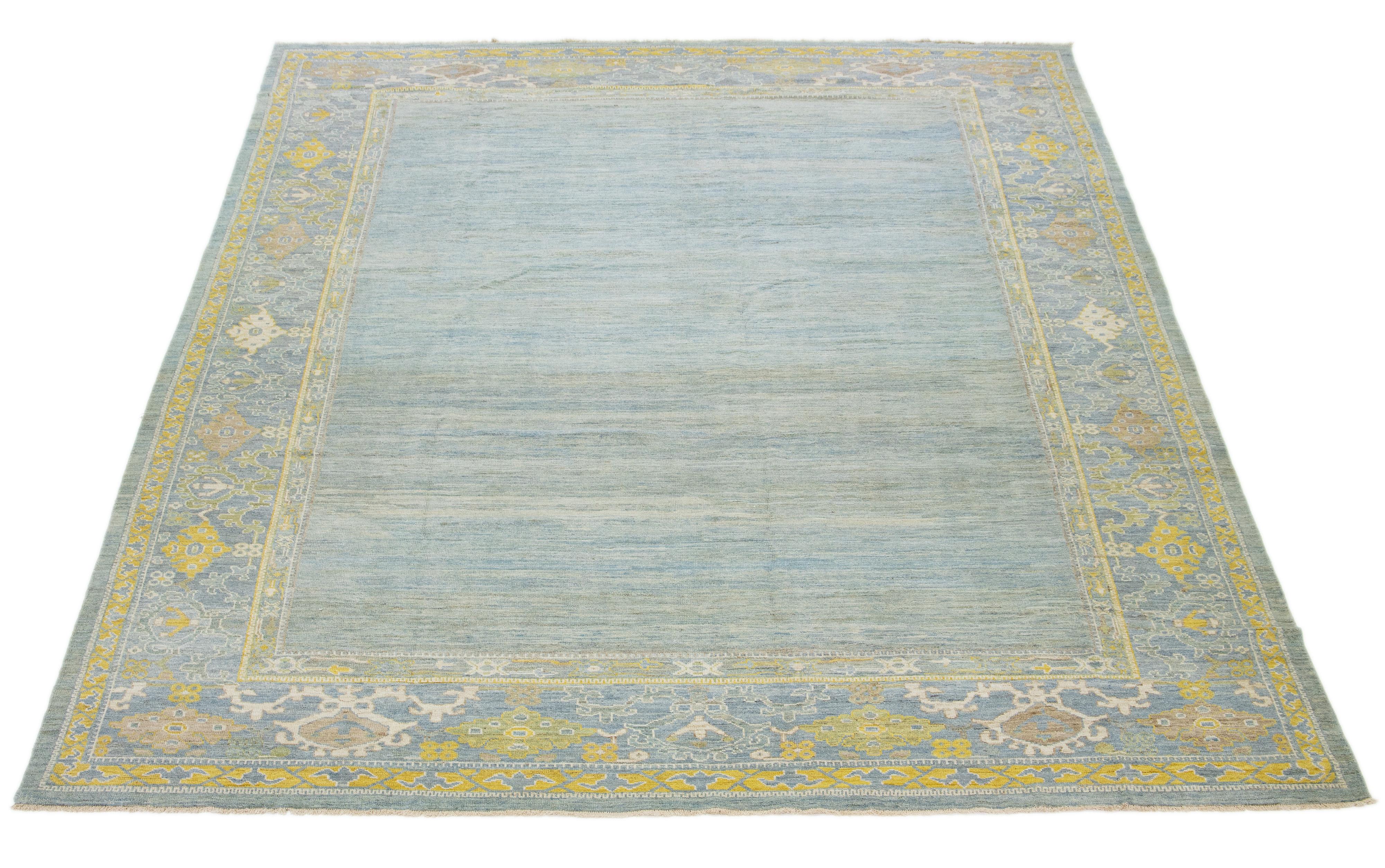 Dieser handgeknüpfte Wollteppich zeigt einen hellblauen Hintergrund mit gelben und beigen Akzenten in einem gerahmten Muster.

Dieser Teppich misst 11'11'' x 15'.