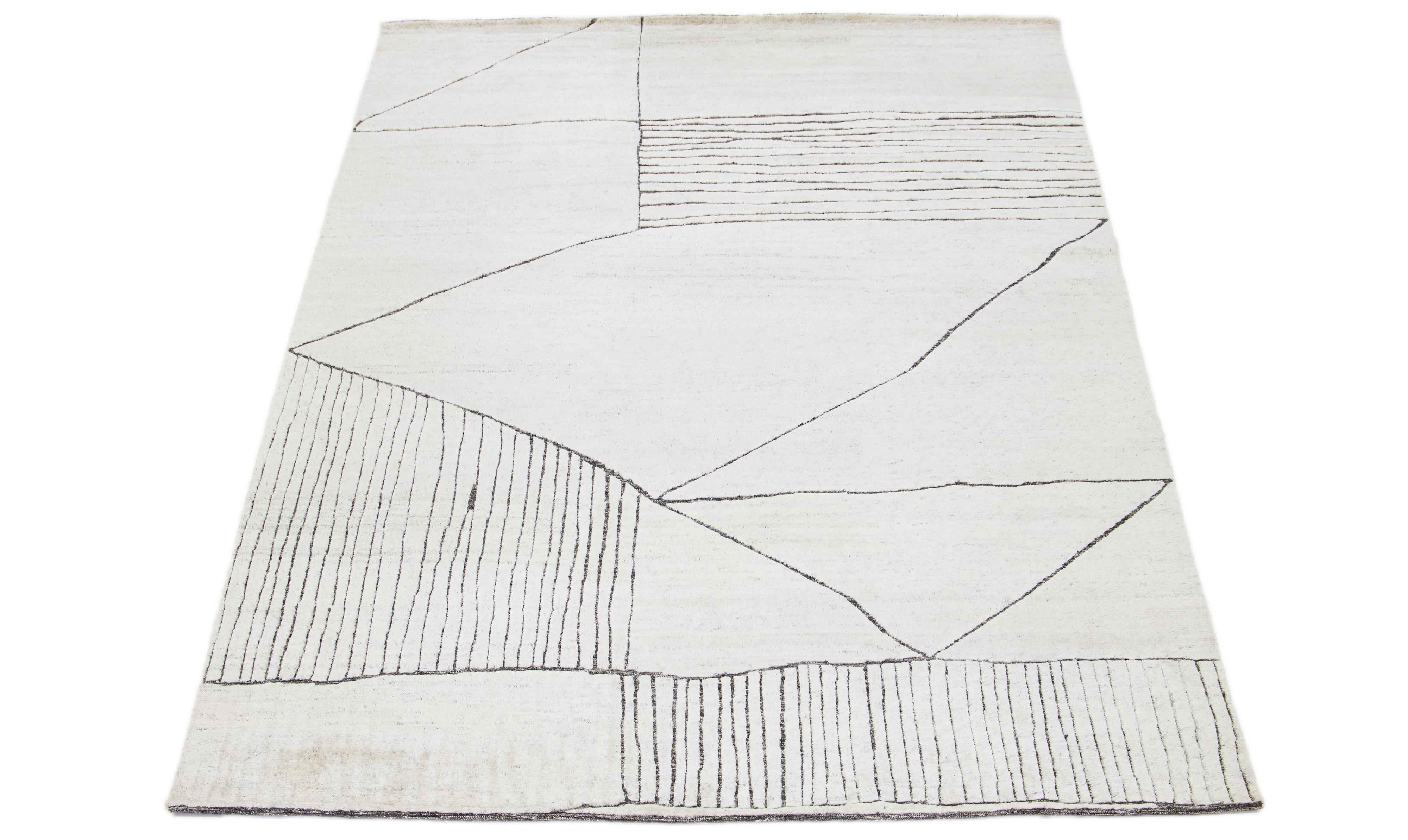 This luxurious wool rug features a timeless Moroccan pattern in a contemporary abstract Minimalist style, utilizing Ivory tones to create a sleek and modern look. It is crafted using traditional hand-knotting techniques, ensuring exceptional quality