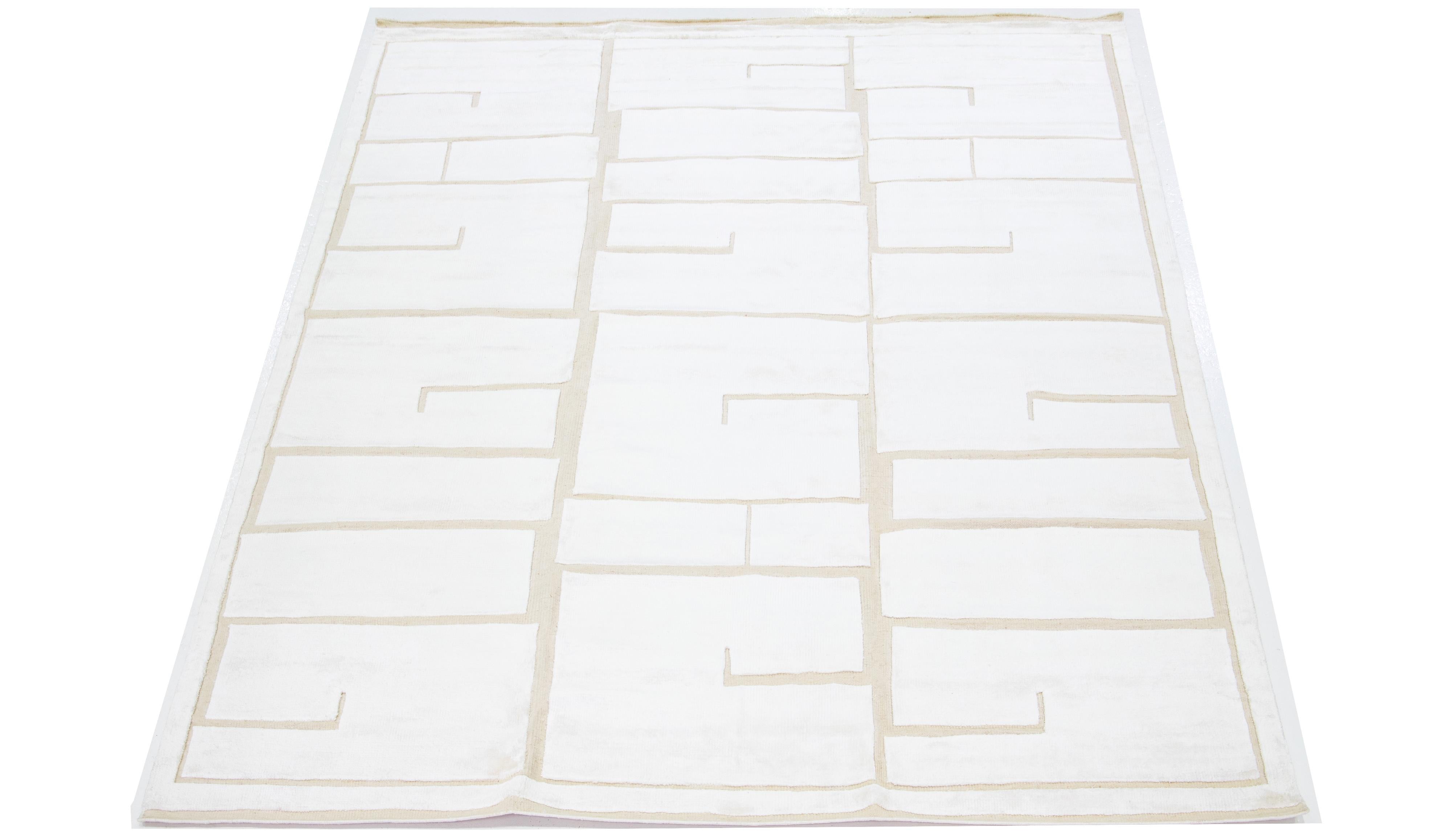 Ce tapis en laine noué à la main présente un motif moderne d'inspiration marocaine mettant en valeur des teintes ivoire discrètes sur une base beige naturelle audacieuse, créant ainsi un design géométrique minimaliste captivant.

Ce tapis mesure