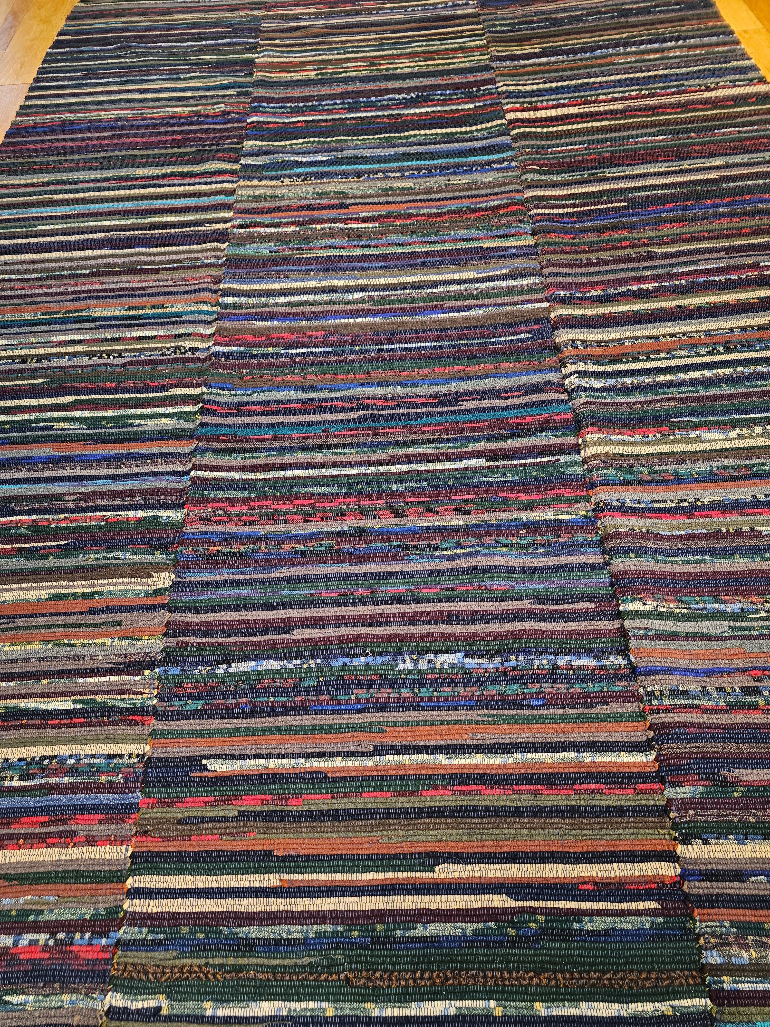 Vintage room size American rag rug in stripe pattern in vibrant colors including various shades of blue, green, red, and ivory from the early-1900s. It has lovely colors and is very well preserved. This American Rag Rug is made of three individual