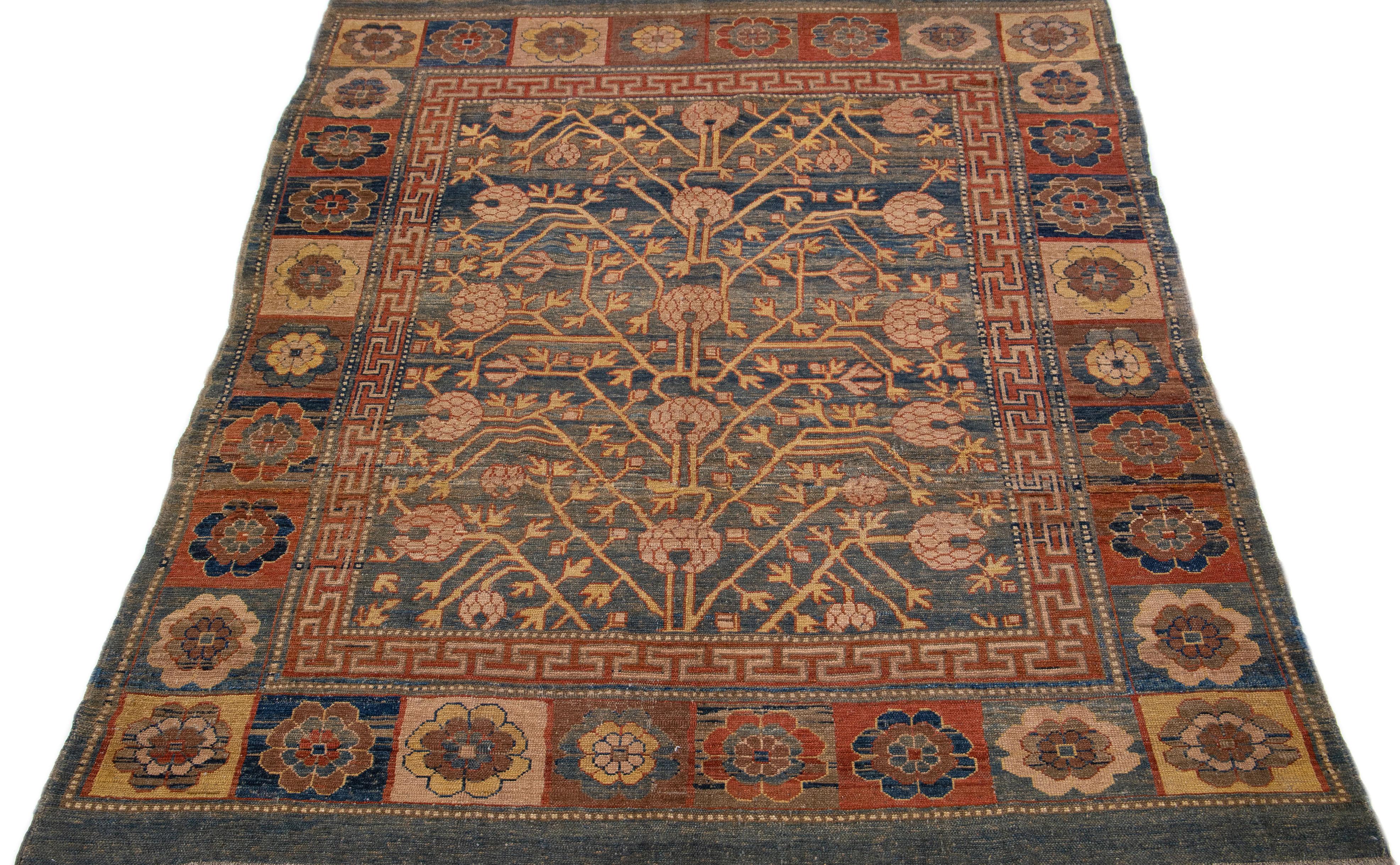Dieser Vintage-Teppich strahlt mit seinem bezaubernden, von Khotan inspirierten Wollmaterial Eleganz aus. Er ist mit einem atemberaubenden blauen Feld und einem komplizierten geometrischen Muster verziert, das durch verschiedene Farben akzentuiert
