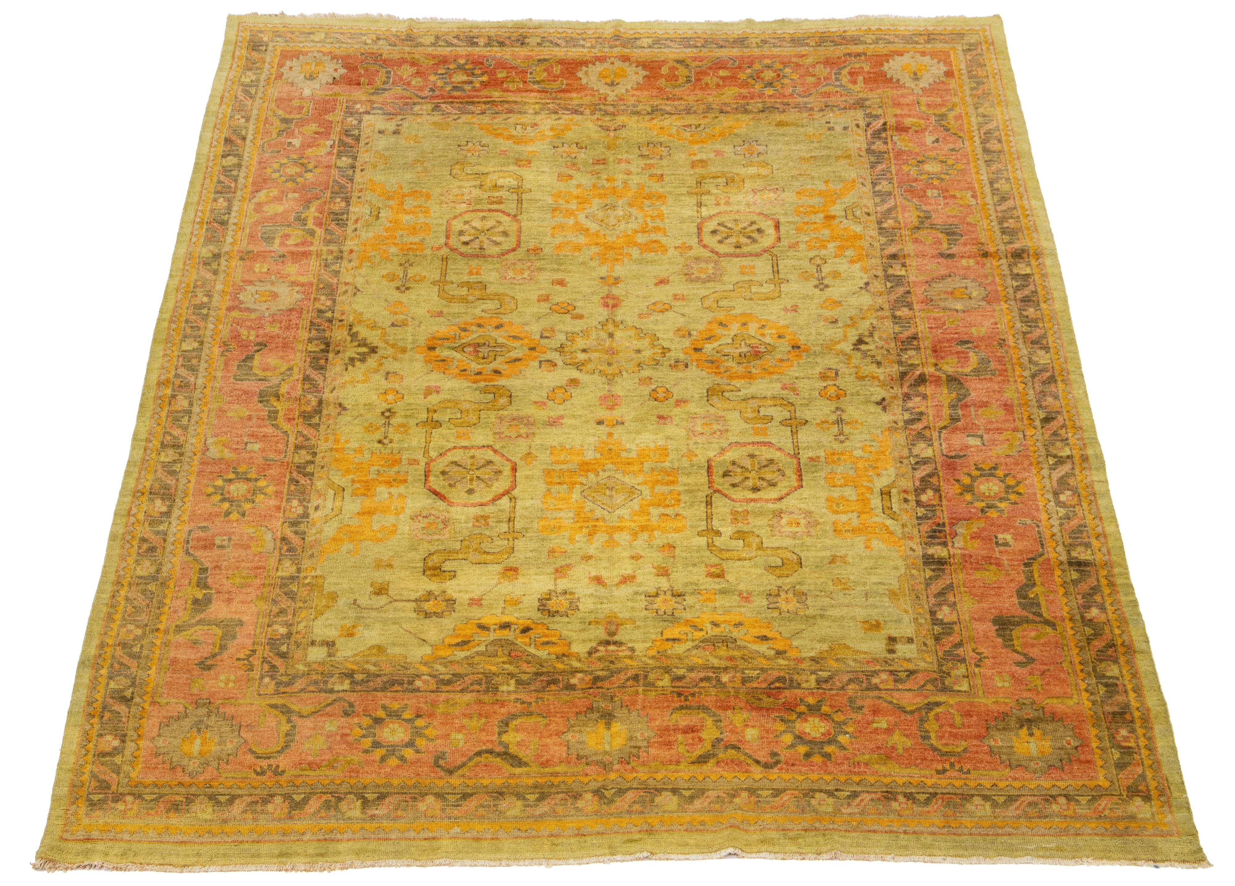 This hand-knotted wool rug features a stunning Vintage Oushak design. Its elegant olive green field is accompanied by classic floral patterns in yellow, gold, and rust shades.

This rug measures 10' x 13'7